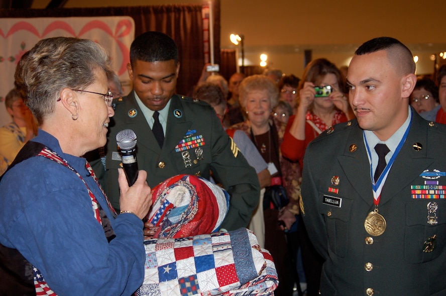 Gail Belmont, operations officer for the Quilts of Valor Foundation, awards quilts to U.S. Army Sgt. Crooks and Sgt. Tabellija during the opening of the Houston International Quilt Festival, Nov. 1, 2007, in Houston, Texas. (Photo courtesy of Catherine C. Roberts, Quilts of Valor Foundation)