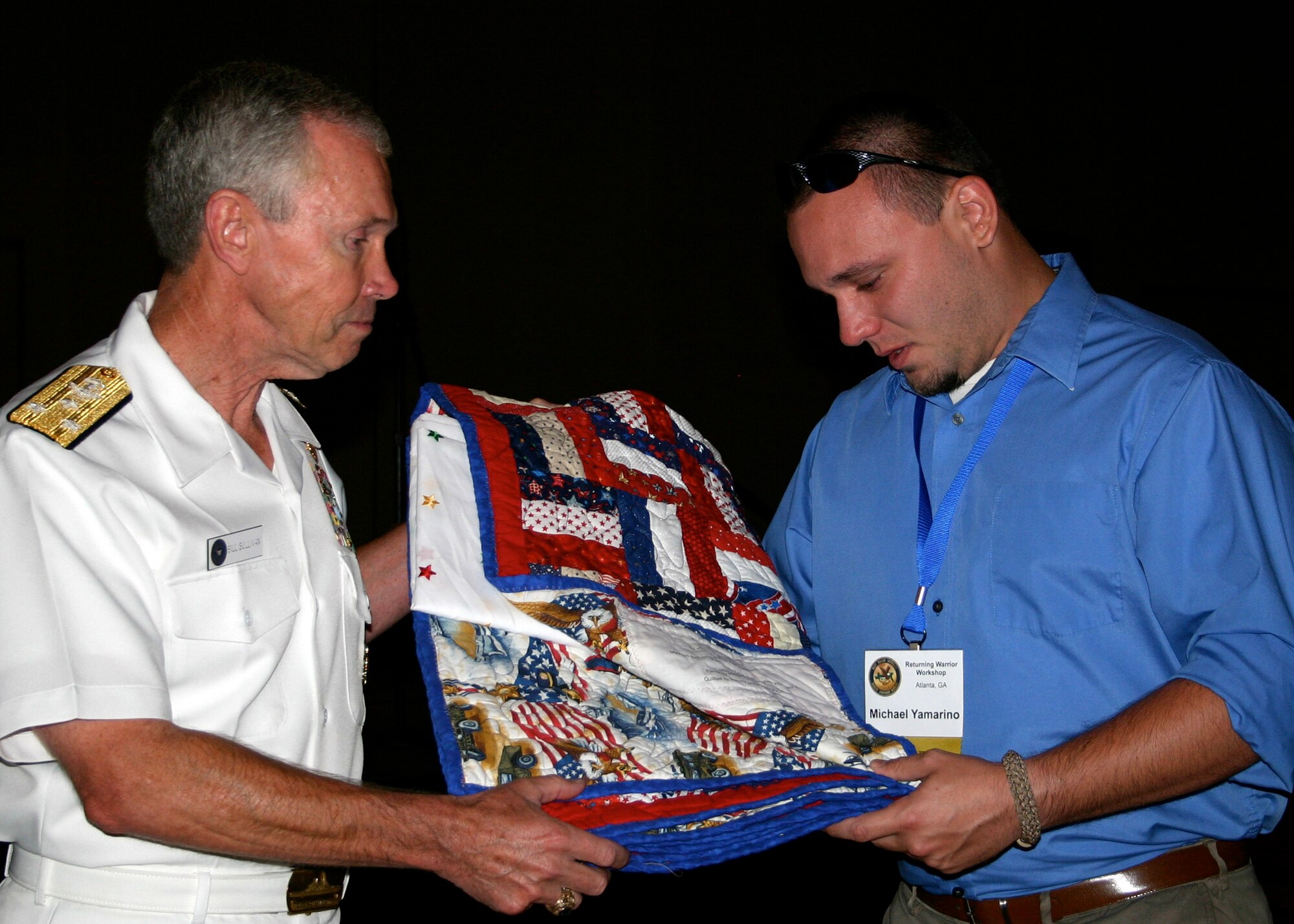 Vice Adm. William D. Sullivan presents Navy veteran Michael Yamarino a quilt of valor during the banquet of honor during the Returning Warrior Workshop in Atlanta, Ga., July 25, 2009. More than 70 Soldiers, Sailors, Marines and their spouses attended the workshop, a national program supporting the ongoing effort to honor and educate those who have mobilized or deployed supporting overseas contingency operations. The workshop includes training sessions and exercises as well as providing attendees an opportunity for counseling in relation to their experiences during their deployment and since returning home. (U.S. Navy photo by Chief Mass Communication Specialist Dawn C. Montgomery/Released)
