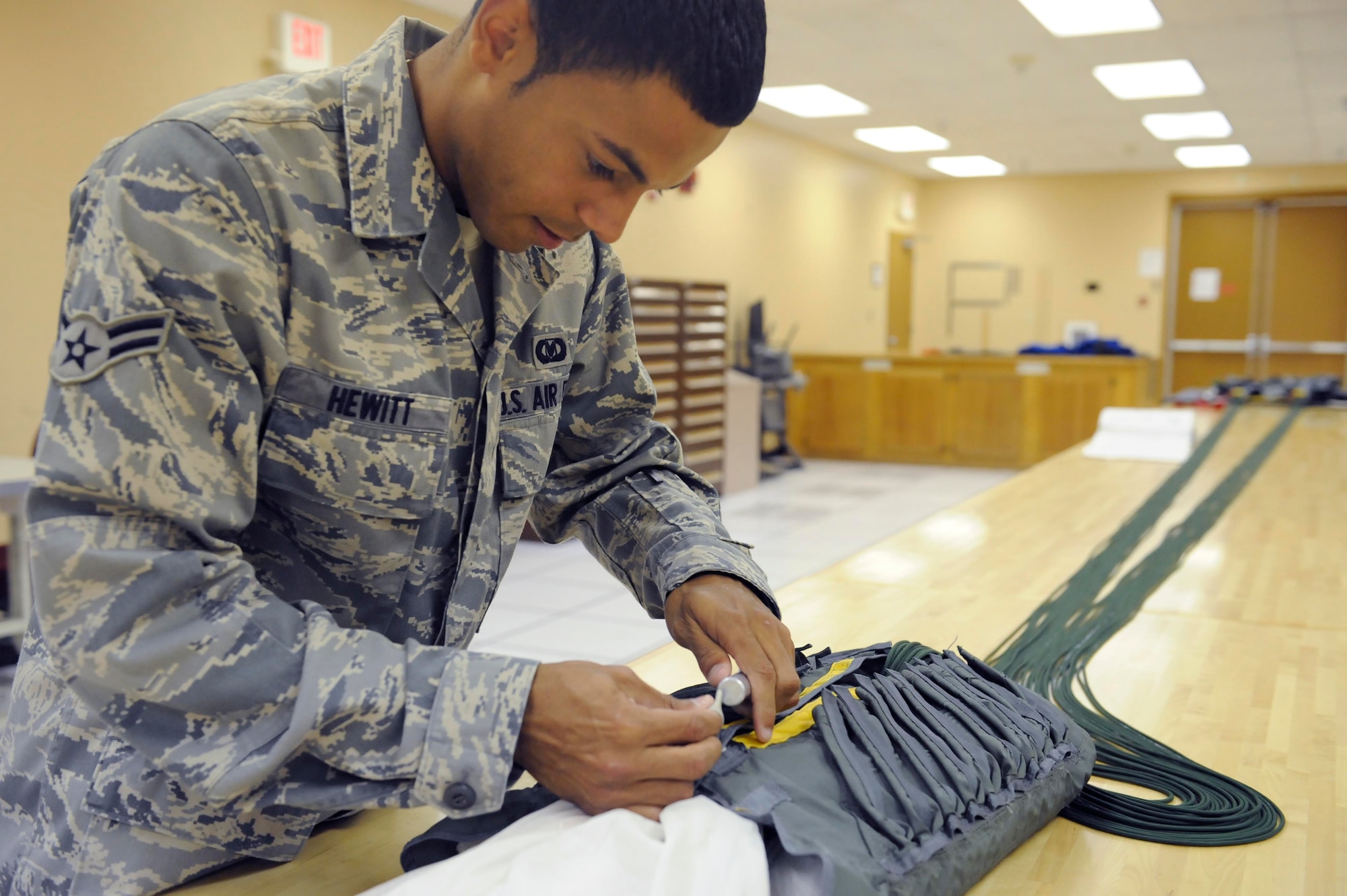 Airman 1st Class Devin Hewitt, 28th Operations Support Squadron aircrew flight equipment apprentice, stows the lines of a back automatic-22 parachute here, August 10. Every inch of the parachute must be inspected before it is considered serviceable for aircrew use. (U.S. Air Force photo by Airman 1st Class Corey Hook)