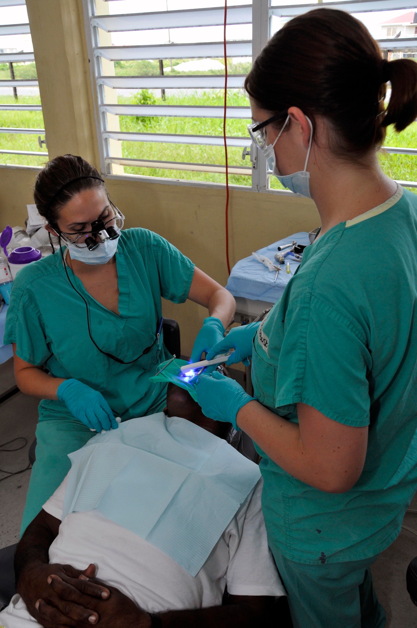 Capt. Kimberly Morio, Dentist, and Senior Airmen Brittany Grabowski, Dental Technician from the 375th Dental Squadron, Scott AFB, Illinois, hardens a Guyanese man's filling with a light curer, during New Horizons Guyana, at the Diamond School Aug 10, 2009, in Diamond, Guyana. New Horizons Guyana 2009 is a U.S. Southern Command-sponsored humanitarian event that will benefit thousands of Guyanese citizens in Georgetown and outlying areas.(U.S. Air Force photo by Airman 1st Class Perry Aston) (Released)