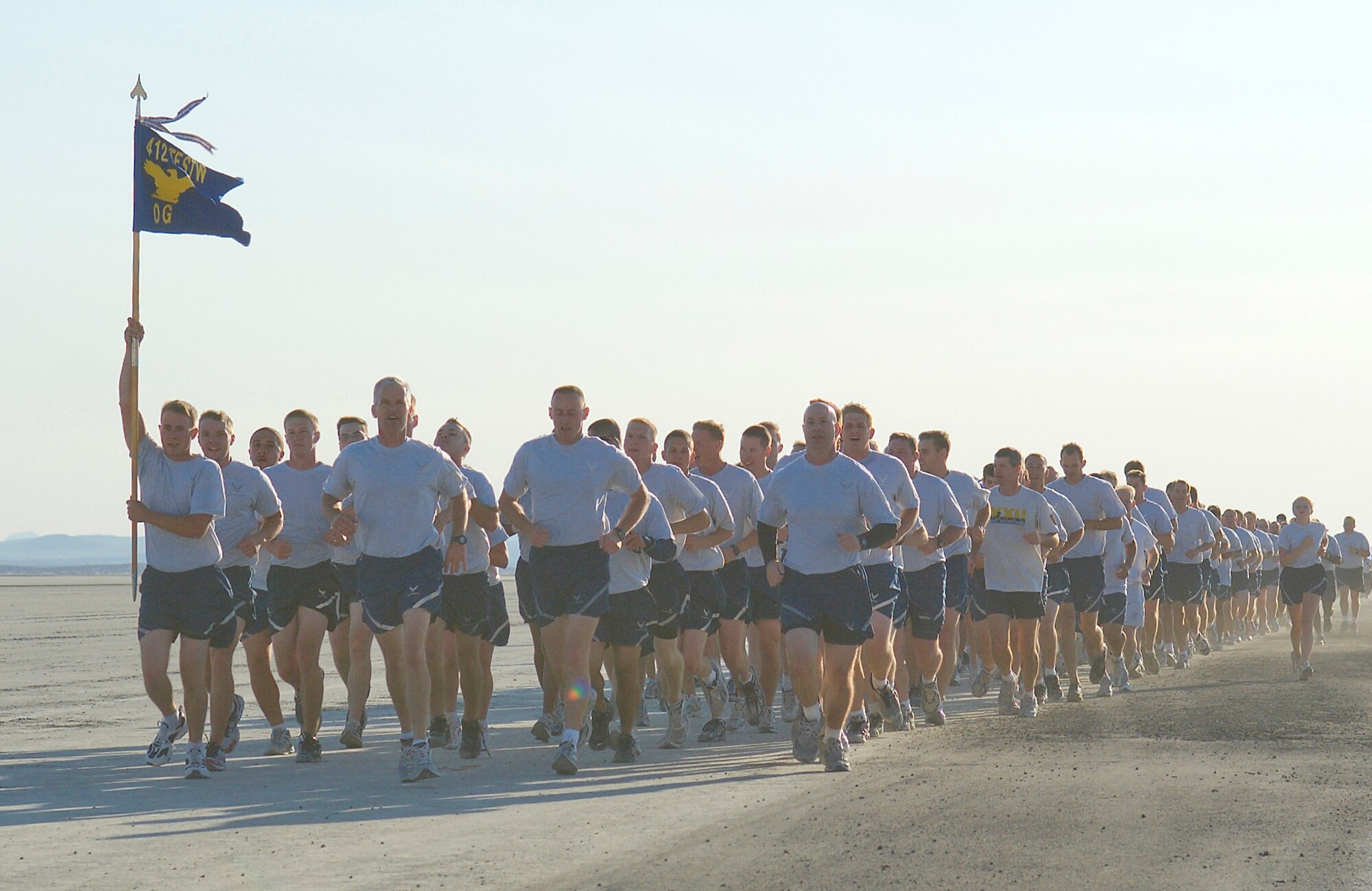 Members of the 412th Test Wing run on Roger's Dry Lakebed during the Installation Fitness Run Aug. 7.  Roger’s Dry Lakebed is compacted clay covering approximately 44 square miles on Edwards with runways used for aircraft emergency landings.  The 2.8-mile run began and finished in front of building 1830.  After leaving the taxi-way, runners were completely surrounded by desert as they watched the base disappear in the distance.  There were no distinguishing landmarks on the dry lakebed; GPS devices were used to lay out the course.  