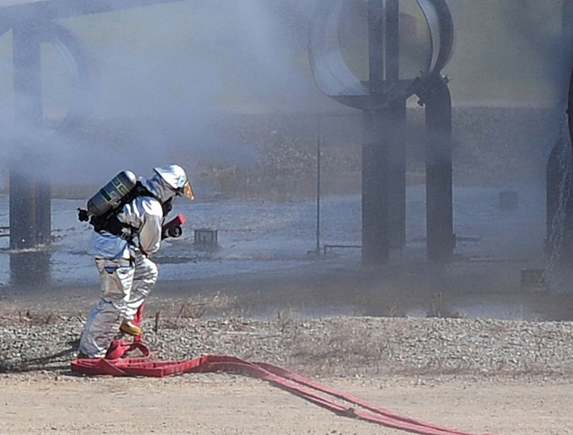 An Airman from the 4th Civil Engineer Squadron Fire Department drags a fire hose to a simulated burning aircraft during a live-fire exercise on Seymour Johnson Air Force Base, N.C., July 31, 2009. These exercises are easily controlled; if something goes wrong, the fire can be extinguished almost immediately by closing the shut-off valve. (U.S. Air Force photo by Airman 1st Class Rae Perry)