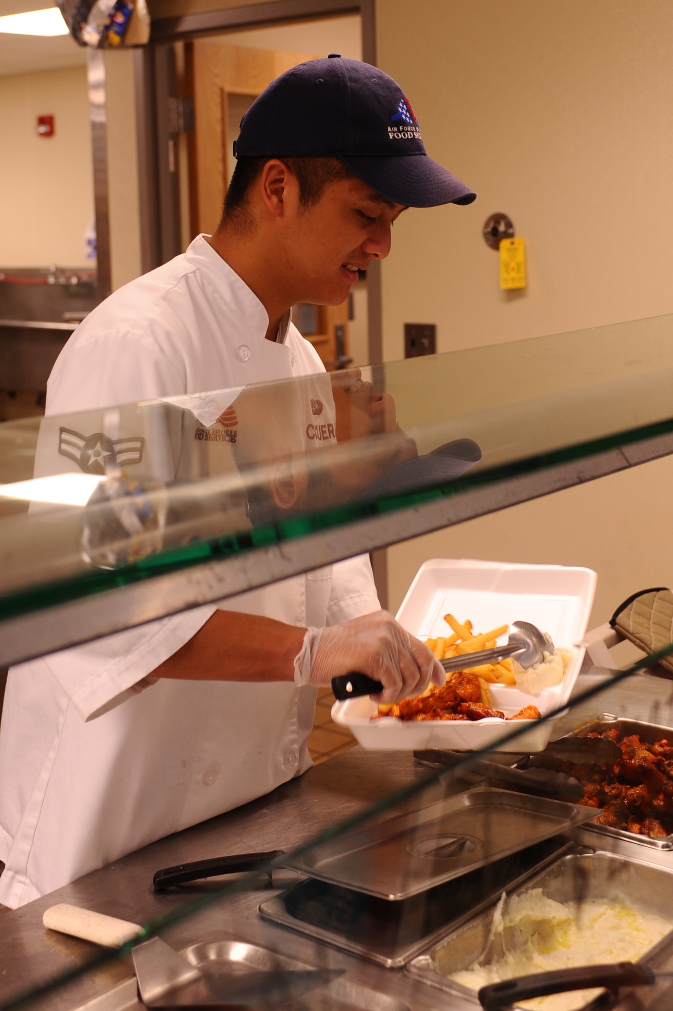 Airman 1st Class Roldan Corcuera, 28th Force Support Squadron food services journeyman, places mashed potatoes in an Airman’s to-go box at the flight kitchen here, August 11. The flight kitchen provides meals for Ellsworth personnel working on the flightline. (U.S. Air Force photo/Senior Airman Kasey Zickmund)