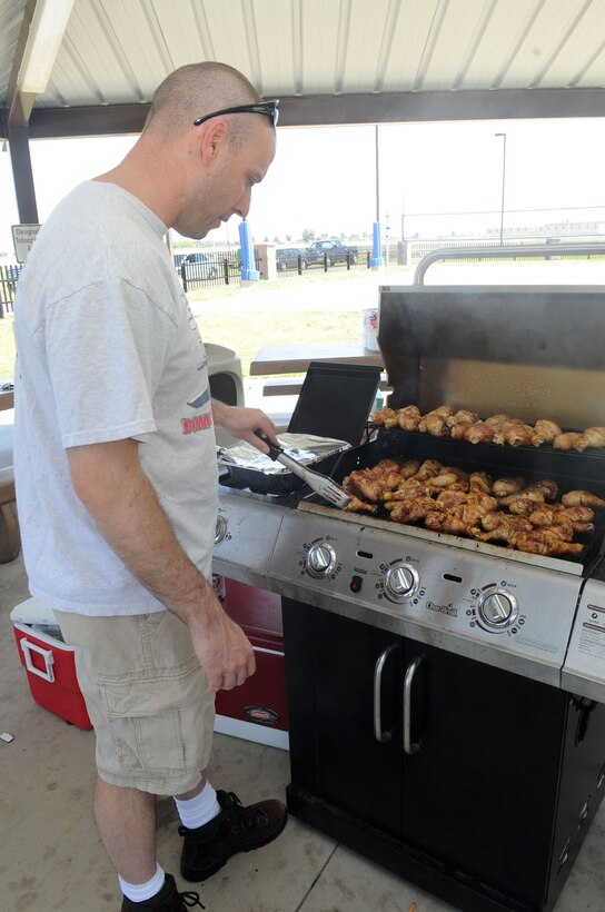 Master Sgt. Mark Pietsch, 566th Intelligence Squadron, prepares chicken drumsticks at the Airman barbecue. Hamburgers and hot dogs were also available for the Airmen living in Patriot Hall. The food was prepared as part of the base-wide power outage. (U.S. Air Force photo by Airman 1st Class Paul Labbe)