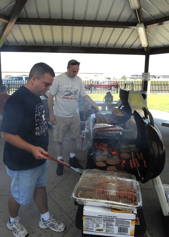 Master Sgts. Mark Pietsch and Jack Smith, 566th Intelligence Squadron, prepare hamburgers and hot dogs at the Airman barbecue Aug. 8. The senior NCOs from the 566th IS were on hand to make sure their Airmen, and all others living in Patriot Hall, were well fed despite the base-wide power outage. (U.S. Air Force photo by Airman 1st Class Paul Labbe)