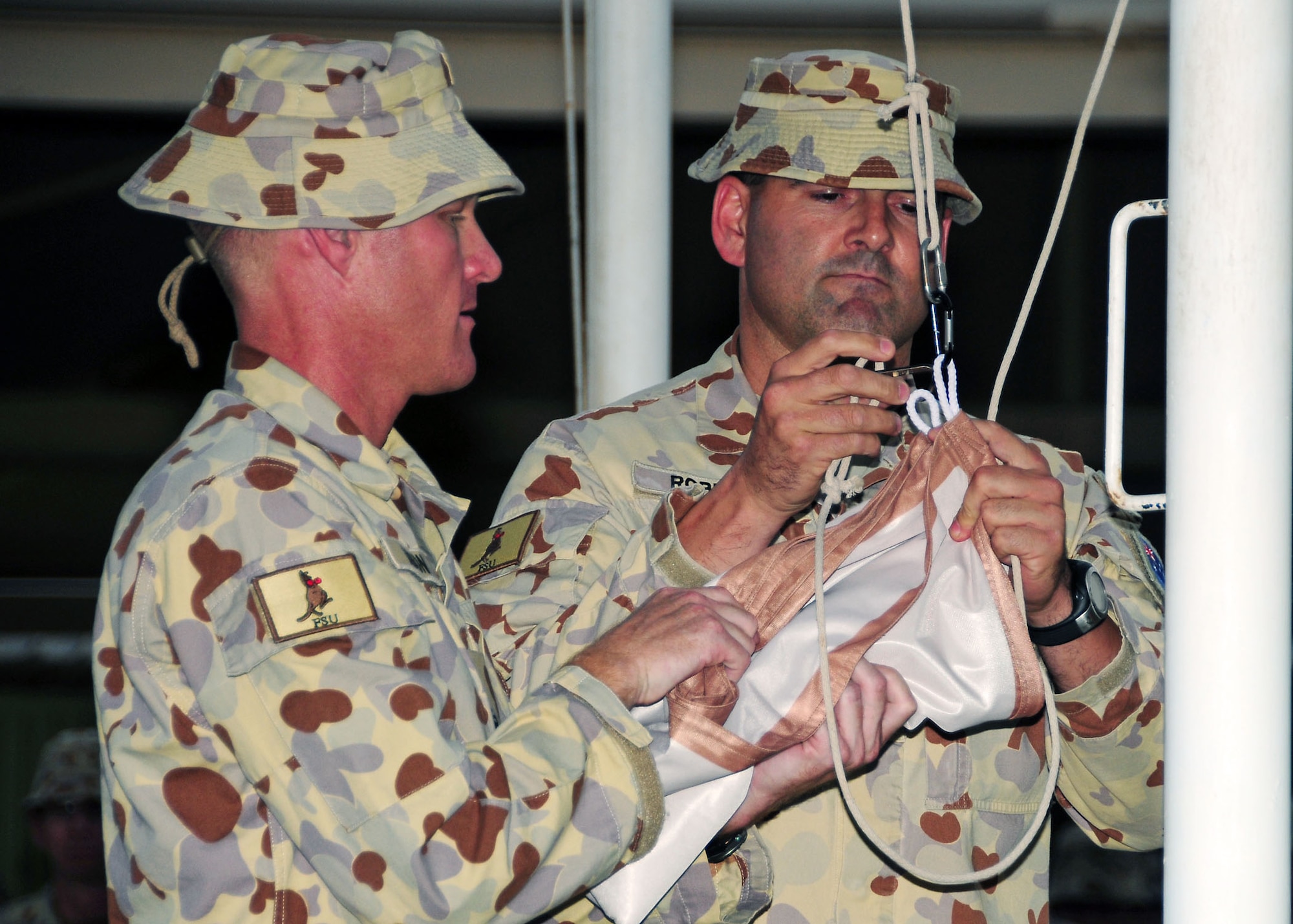 SOUTHWEST ASIA-- Lt. Col. Craig Dobson (left), and RSM-WO1 Andrew Roberts prepare to fly the Australian Defence Force Support Unit Two flag during a transfer of authority ceremony at an undisclosed location in Southwest Asia August 11.  Lt. Col. Dobson assumes command of Force Support Unit Two after Force Support Unit One  served a six month tour of duty.  (U.S. Air Force photo/Tech Sgt. Tony Tolley)