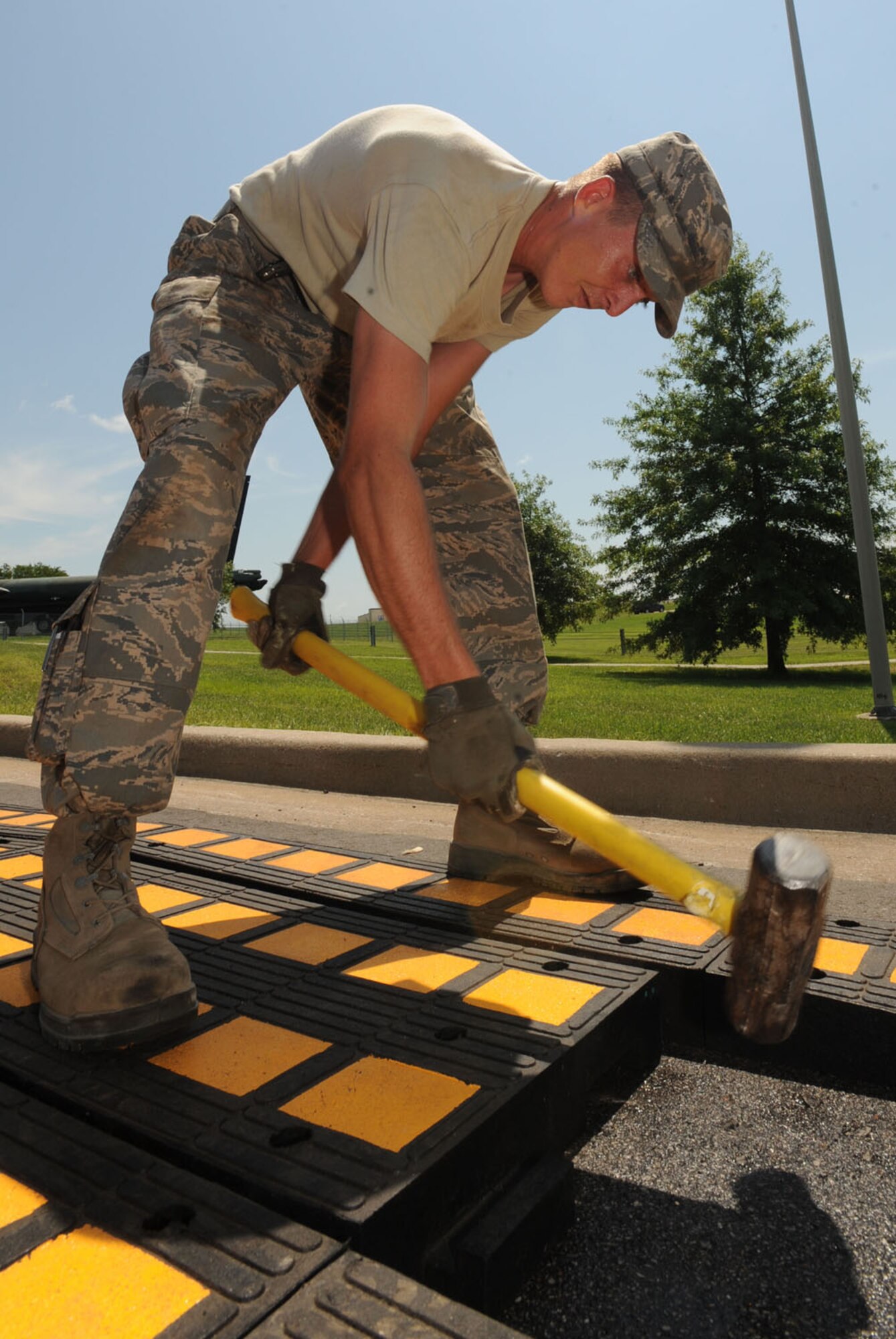 WHITEMAN AIR FORCE BASE, Mo. – Airman 1st Class Johnathan Goodwin, 509th Civil Engineer Squadron, uses a sledge hammer to shift new speed hump tiles into position near Arnold Gate, Aug.11.  Each individual piece of the speed humps must laid out and be predrilled then bolted down. Arnold gate is receiving three of these new fixtures to be completed by Aug. 12. The Lemay and Spirit gates will also be receiving these fixtures in the upcoming weeks. (U.S. Air Force Photo/Airman First Class Carlin Leslie)