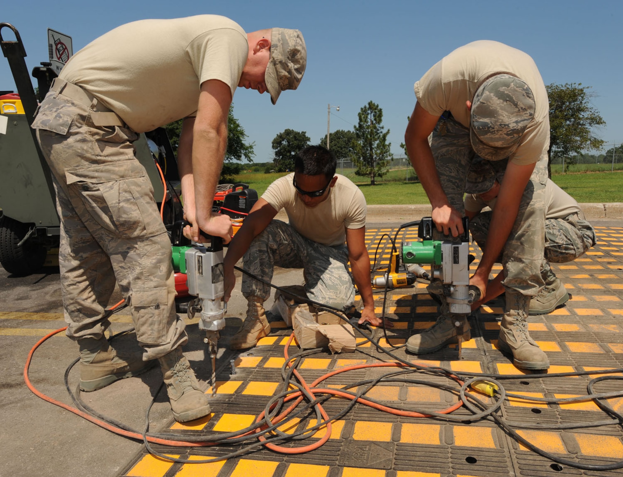 WHITEMAN AIR FORCE BASE, Mo. – Three Airman from the 509th Civil Engineer Squadron pre-drill holes through new speed humps for install near the Arnold Gate, Aug 11. Each individual piece of the speed humps must laid out and be predrilled then bolted down. Arnold gate is receiving three of these new fixtures to be completed by Aug. 12. The Lemay and Spirit gates will also be receiving these fixtures in the upcoming weeks. (U.S. Air Force Photo/Airman First Class Carlin Leslie)