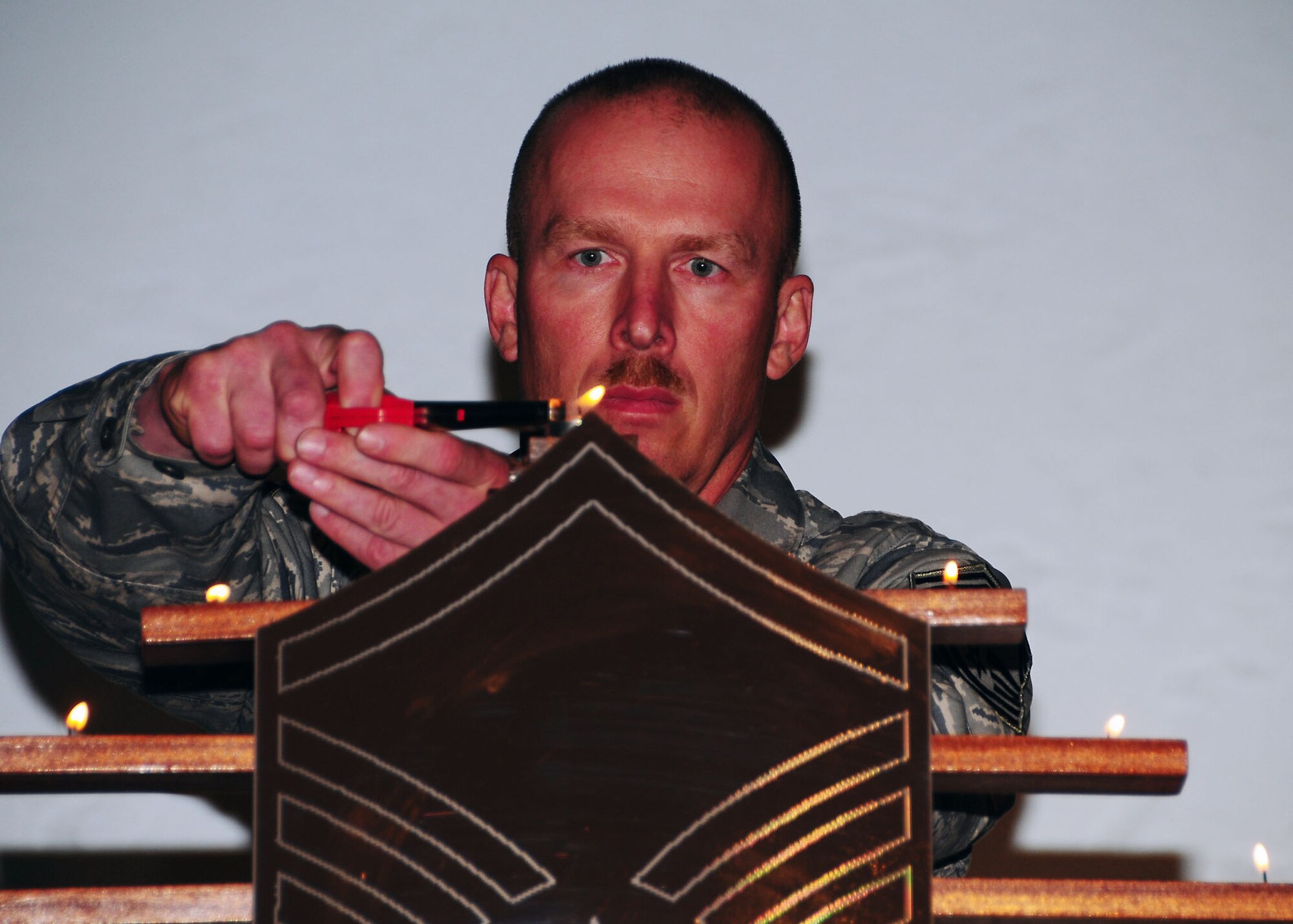 SOUTHWEST ASIA -- Chief Master Sgt. Garth Freund, 386th Expeditionary Security Forces Squadron manager, lights the last of nine candles representing each enlisted rank in the U.S. Air Force during the senior non-commissioned officer induction ceremony held here  Aug. 8. Thirteen NCOs from the 386th Air Expeditionary Wing were inducted into the Senior NCO corps during the tradition-rich ceremony. (U.S. Air Force photo/Tech. Sgt. Tony Tolley)  