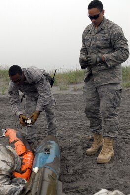 Staff Sgt. Michael Overton and Airman 1st Class William Holliday, 35th Civil Engineer Squadron explosive ordnance disposal technicians, prepare bomb dummy unit for detonation Aug. 7 at Draughon Range. The technicians used C4 to smash the body of the bomb to exposing the internal elements. (Air Force photo/Staff Sgt. Phillip Butterfield) 
