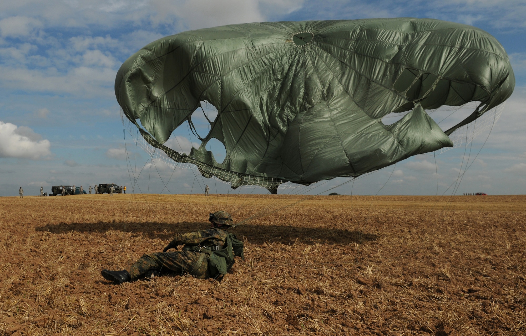 German Army soldier Christian Schlueter lands after parachuting out of a C-130 Hercules on Bunker drop zone in southwestern, Germany on Aug. 13, 2009. U.S. soldiers and airmen performed a combined airborne drop with four other NATO countries. German, Italian, Belgium, and Dutch army attended the airborne drop during NATO Jump Week. (U.S. Air Force photo by Airman 1st Class Grovert Fuentes-Contreras)
