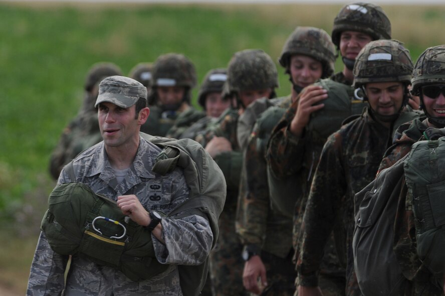 U.S. Air Force Staff Sgt. Joseph Klimaski, 435th Security Forces Squadron, walks off the field with German soldiers after landing at Bunker drop zone in southwestern, Germany on Aug. 13, 2009. U.S. Soldiers and Airmen performed a combined airborne jump with four other NATO countries. German, Italian, Belgium, and Dutch Army attended the airborne jump during International Jump Week. (U.S. Air Force photo by Airman 1st Class Grovert Fuentes-Contreras) 
