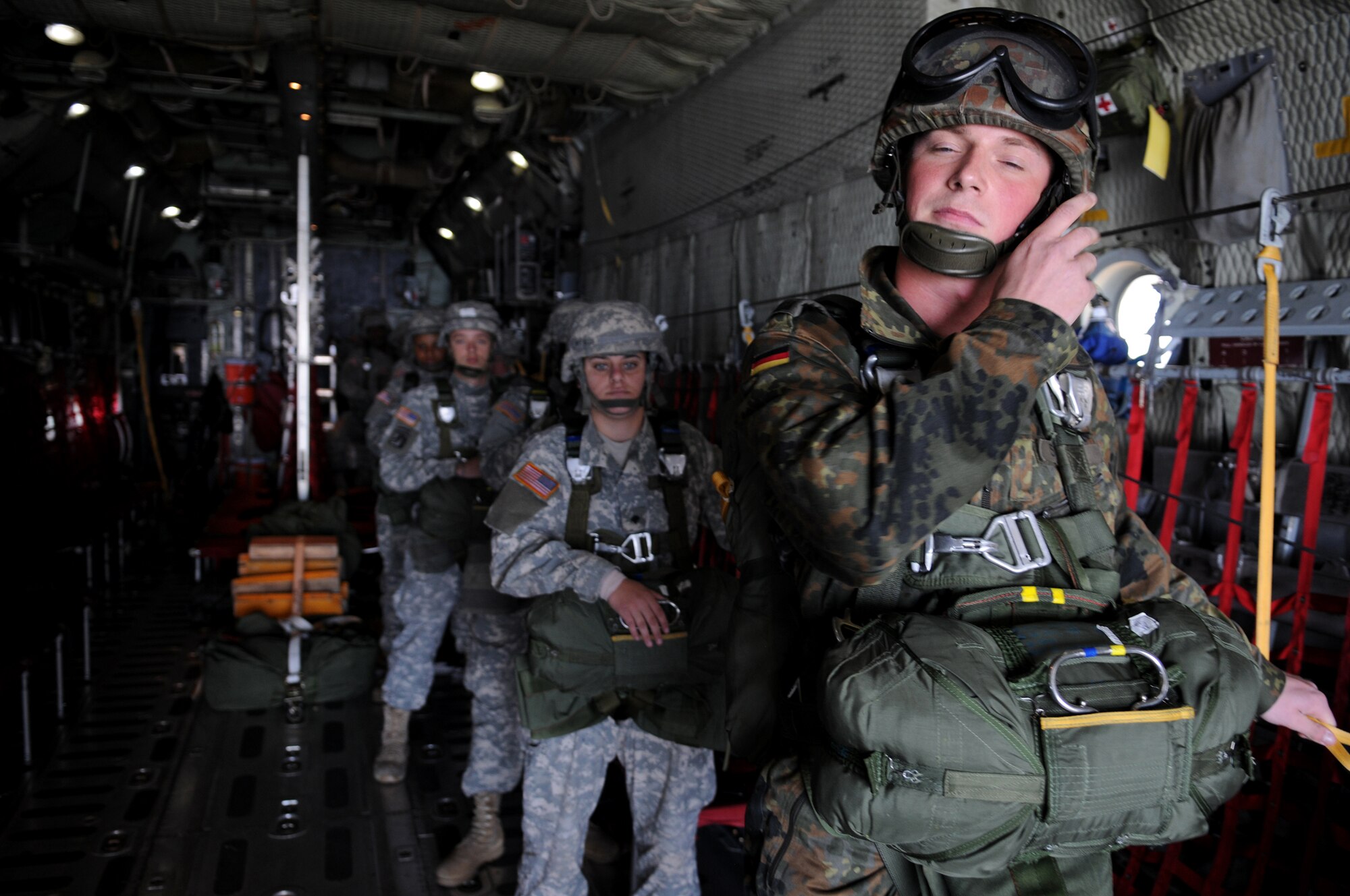German Army Christian Schlueter ensures his safety before parachuting out of a C-130 Hercules over Bunker drop zone in southwestern, Germany on Aug. 12, 2009. Normally led by a U.S. soldier, German soldier Schlueter lead an entire U.S. Army jump line. U.S. soldiers and airmen performed a combined airborne jump with four other NATO countries. German, Italian, Belgium, and Dutch army attended the airborne jump during NATO Jump Week. (U.S. Air Force photo by Airman 1st Class Grovert Fuentes-Contreras)