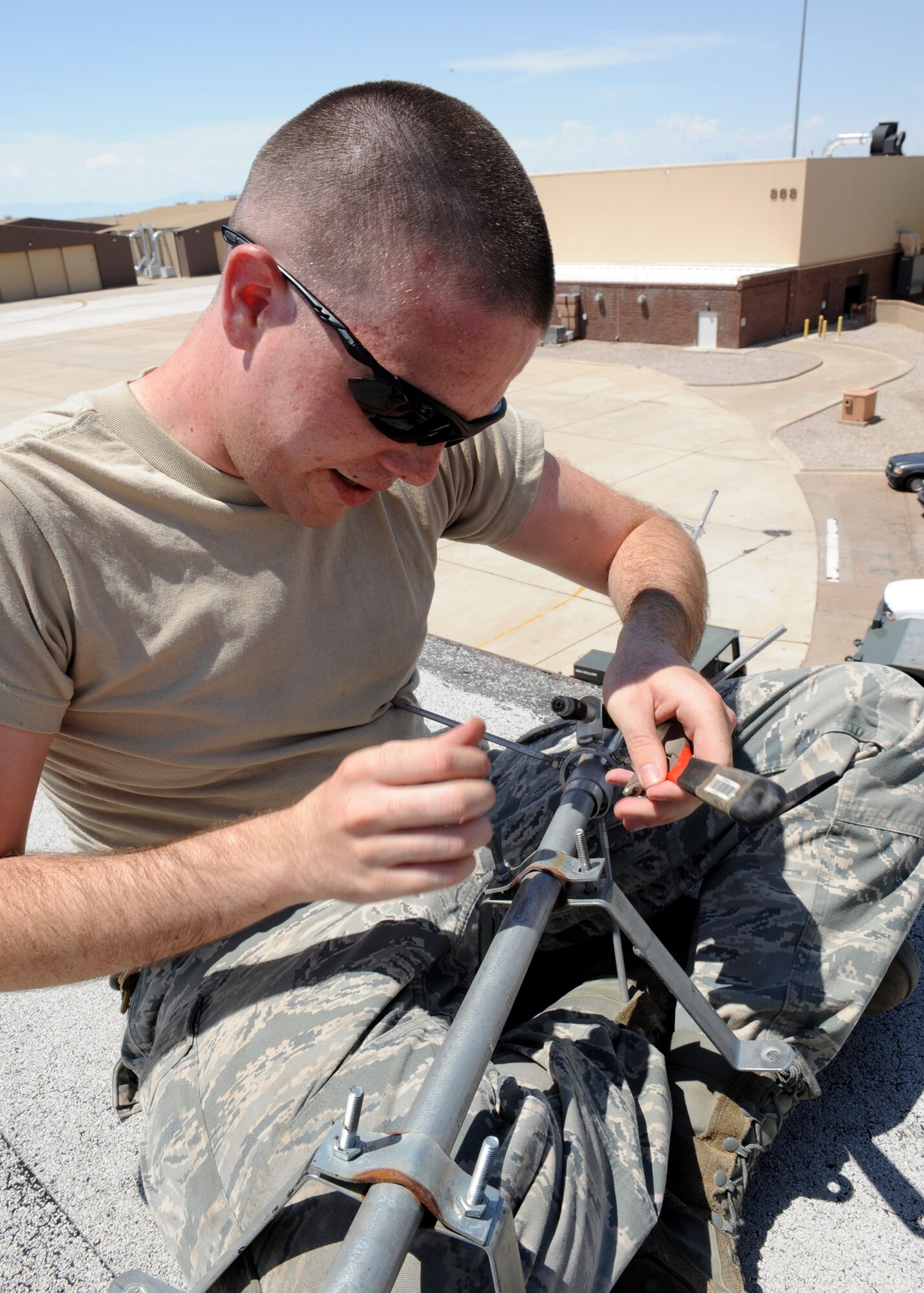 HOLLOMAN AIR FORCE BASE, N.M. -- Airman 1st Class Joseph Meade, 49th Communications squadron, removes an old mounting bracket from an antenna on the roof of Building 877 here Aug. 12.  Antennas can also be operated under water or even through soil and rock at certain frequencies for short distances. (U.S. Air Force photo by Senior Airman Rachel Kocin)
