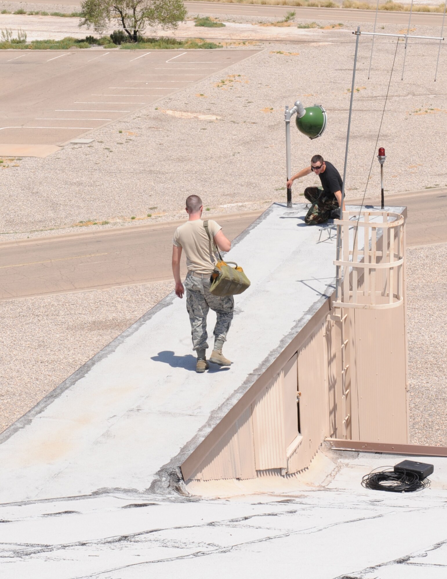HOLLOMAN AIR FORCE BASE, N.M. -- Airman 1st Class Joseph Meade and Senior Airman Nicholas Comtois, 49th Communications Squadron, move an antenna from the roof of Building 877 here Aug. 12. The antenna was moved due to a customer relocation request. (U.S. Air Force photo by Senior Airman Rachel Kocin)