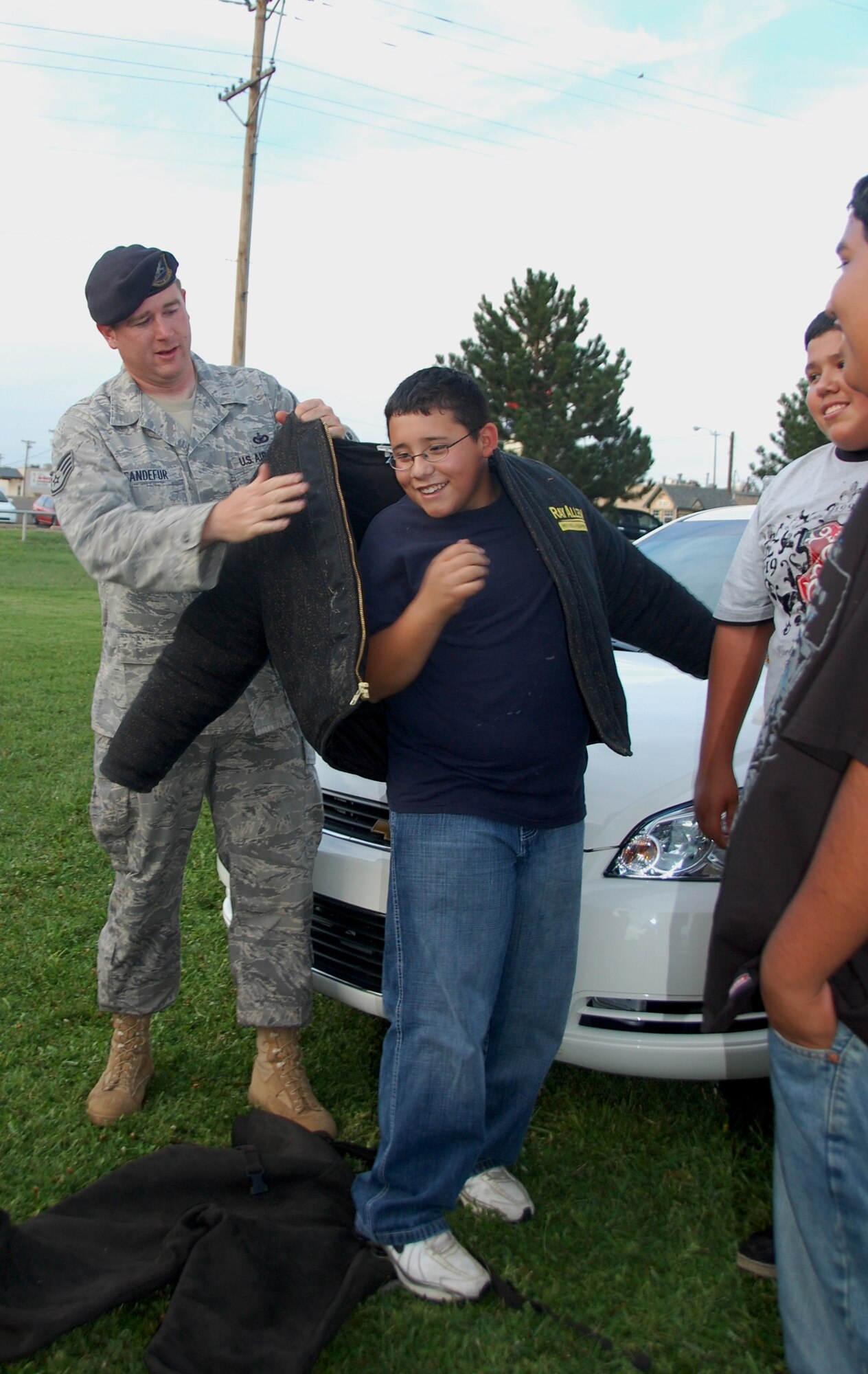 CANNON AIR FORCE BASE, N.M. -- Staff Sgt.  Christopher Sandefur, 27th Special Operations Security Forces Squadron, helps a local youth put on a K-9 bite suit during National Night Out Aug. 4 at Green Acres Park, Clovis N.M. The  suit weighs about 20 pounds and protects K-9 handlers when they train with Military Working Dogs. (Air Force photo by Tech Sgt. Gloria Wilson) 