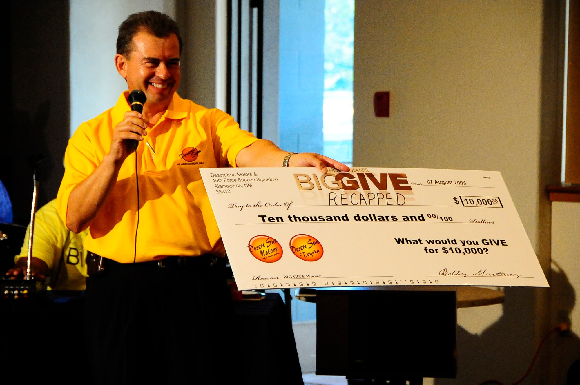 HOLLOMAN AIR FORCE BASE, N.M. -- Bobby Martinez, owner of Desert Sun Motors of Alamogordo, N.M., presents a check for $10,000 to the winning team of the 2009 Big Give, Team RECAPPED, during the after-party here Aug. 7. Mr. Martinez said it was the "greatest $10,000 he's ever spent." (U.S. Air Force photo by Tech. Sgt. Chris Flahive)