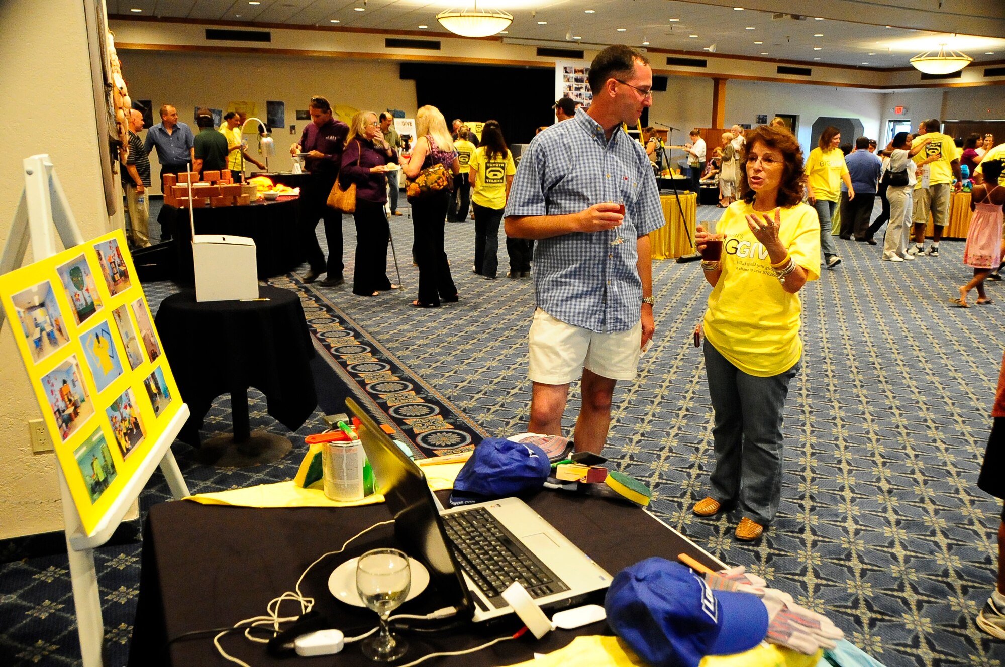 HOLLOMAN AIR FORCE BASE, N.M. -- Eva Van Horn, 49th Force Support Squadron and member of Team Hungry Hungry Helpers, explains to Col. Stephen DiFonzo, 49th Mission Support Group commander, what her team did for the Big Give at the after-party here Aug. 7. Hungry Hungry Helpers did renovations for the La Vida Learning Institute and painted a large mural for the children of the institute to enjoy. The project was showcased at their team display table at the after-party. (U.S. Air Force photo by Tech. Sgt. Chris Flahive)