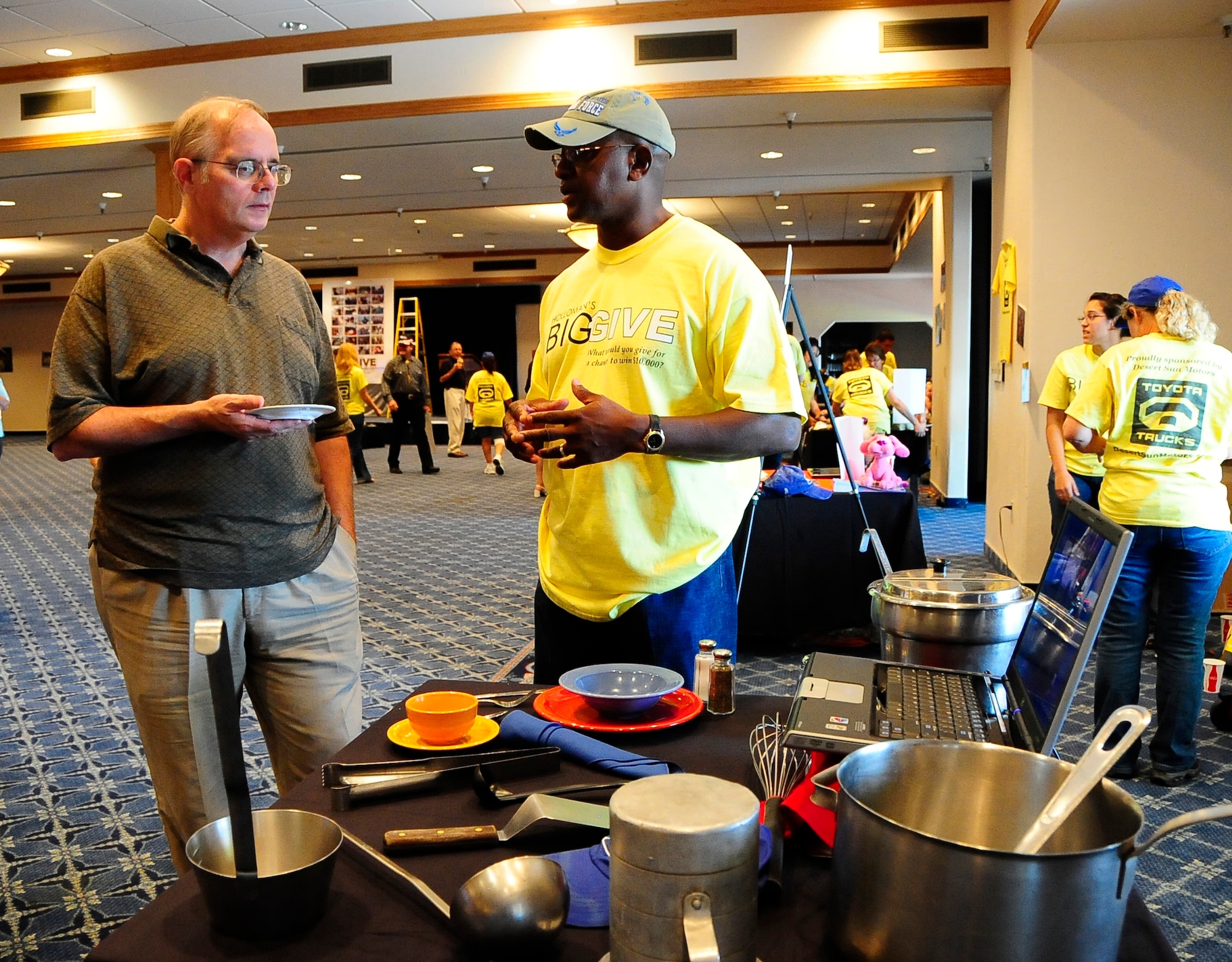 HOLLOMAN AIR FORCE BASE, N.M. -- Chief Master Sgt. Jerome Baker, 49th Mission Support Group, explains to Dave Lucoski, 49th Mission Support Group, what Team Desert Dawgs did for the Big Give during the after-party here Aug. 7. Team Desert Dawgs provided home-cooked meals to more than 540 homeless people in the local community during their three-week endeavor. (U.S. Air Force photo by Tech. Sgt. Chris Flahive)