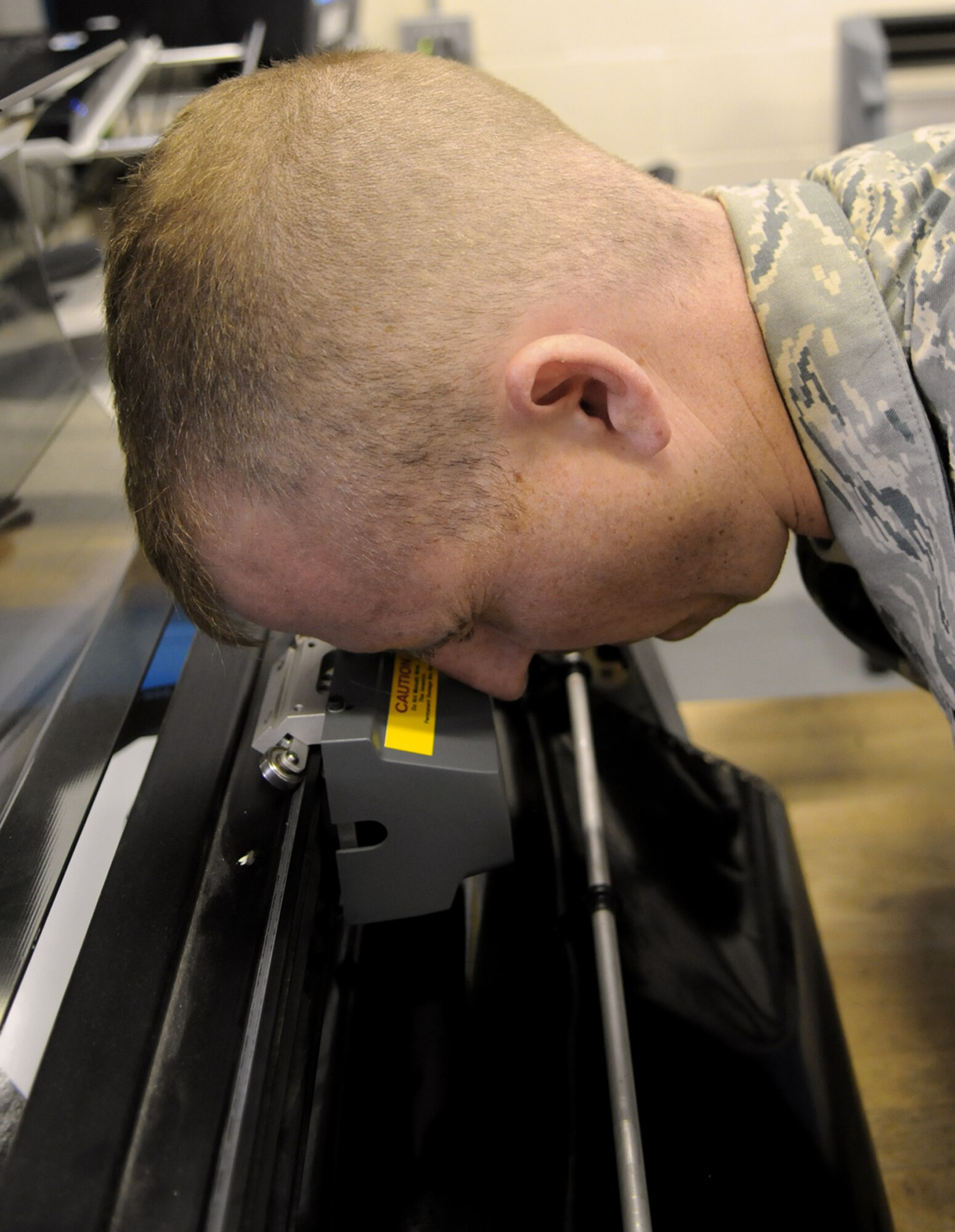 Staff Sgt. Christopher Breaux uses a "bomb sight" to line up a precision cutting blade on an automated machine which will be used to score the material of a new decal Aug. 13 at Royal Air Force Mildenhall, England. The 100th Air Refueling Wing's corrosion control shop creates decals and applies paint to every aircraft needing it at RAF Mildenhall. Sergeant Breaux is an aircraft structural maintenance craftsman. (U.S. Air Force photo/Staff Sgt. Austin M. May) 