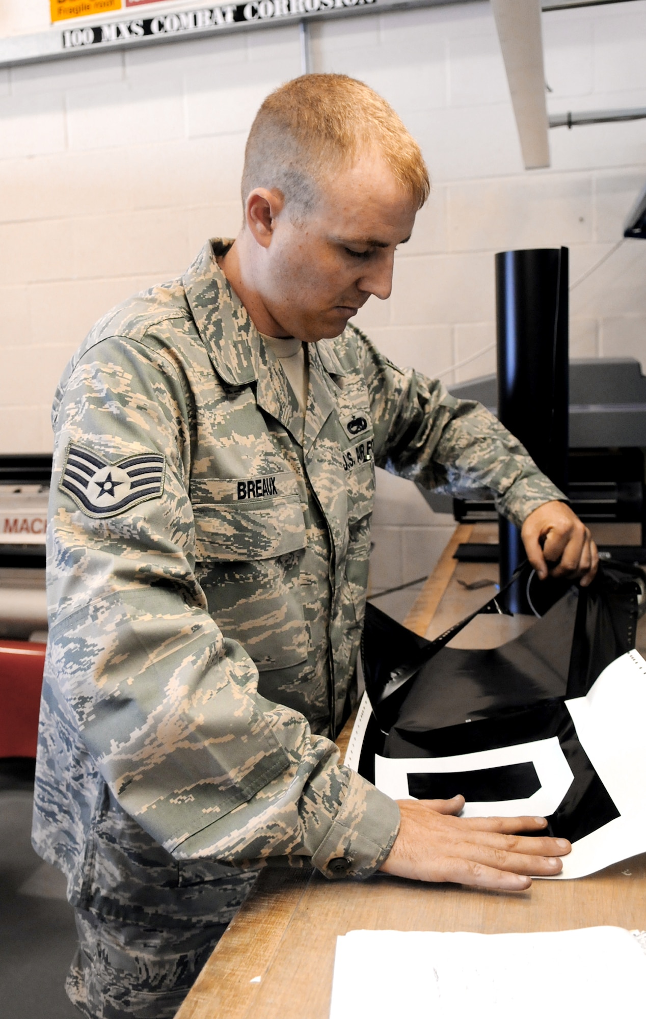 Staff Sgt. Christopher Breaux removes excess material from a scale decal of the "Box D" seen on the tail of all 100th Air Refueling Wing KC-135 Stratotankers Aug. 13 at Royal Air Force Mildenhall, England. The actual decal used on the jets is four times as large as the one seen here and is split into four different pieces. Sergeant Breaux is an aircraft structural maintenance craftsman. (U.S. Air Force photo/Staff Sgt. Austin M. May) 