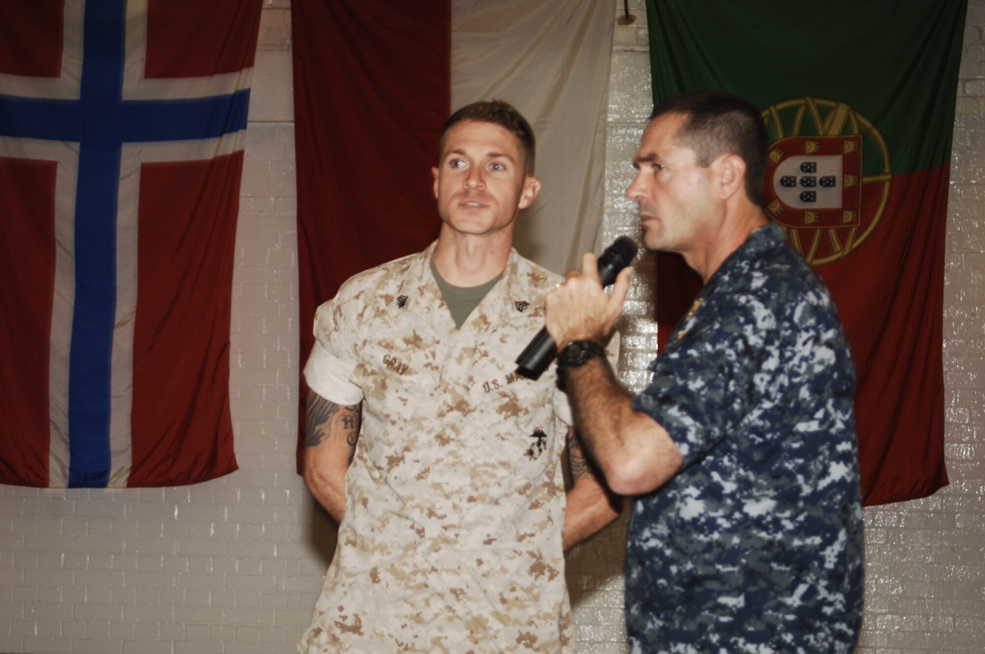 Marine Corps Sergeant Tyler C. Gray and Fleet Master Chief Roy M. Maddocks, Jr. scan the crowd during an all-hands at RAF Molesworth for Army Specialist Leon E. McCree who Gray has just nominated to recieve a surprise unit coin from the U.S. European Command Senior Enlisted leader.  (U.S. Air Force photo by Staff Sgt. Rachel A. Goff)    