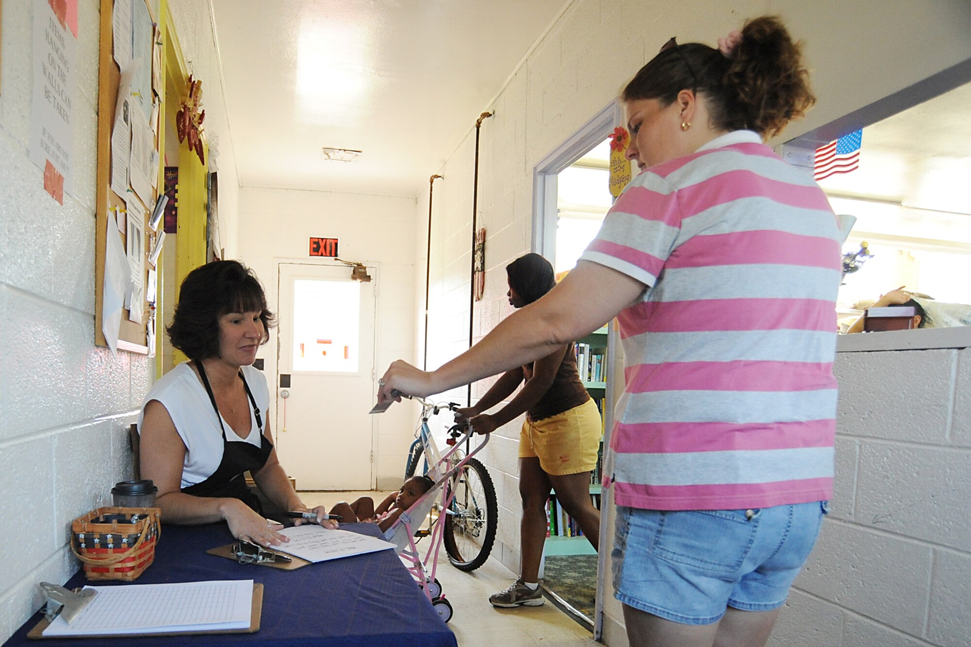 Lisa McClain, Airman's Attic volunteer, greets and checks identification cards as dependants enter the Seymour Johnson Airman's Attic, Aug. 5, 2009. Mrs. McClain has been volunteering at the Airman's Attic and Thrift Shop since 2005. The Airman's Attic is open to E-6s and below, who may grab an unlimited amount of free household goods, children's toys and clothing. (U.S. Air Force photo by Airman 1st Class Whitney Lambert)