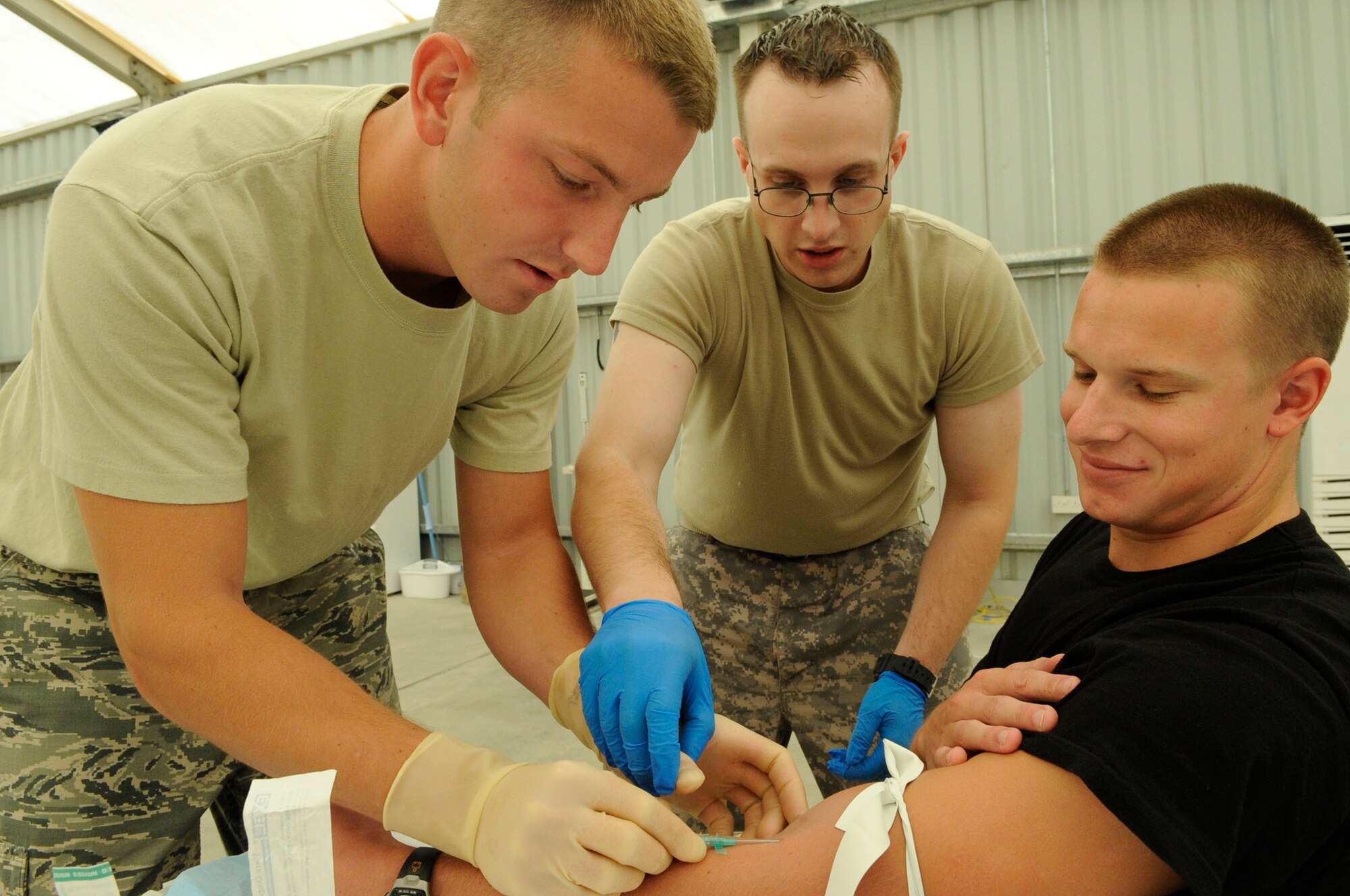 SOUTHWEST ASIA – Staff Sgt. Joshua Hartwell, 380th Expeditionary Civil Engineer Squadron, gives Senior Airman Kyle Dobler, 380th ECES, an IV as Specialist Bryan Haney, a U.S. Army medic, supervises during a Combat Lifesaver Course Aug. 13. The course teaches them to become a bridge between basic self aid and buddy care and combat medics. Sergeant Hartwell is deployed from McConnell AFB, Kan., and hails from Warner Robins, Ga. Airman Dobler is deployed from Peterson AFB, Colo., and hails from Vacaville, Calif. Specialist Haney is deployed from Fort Bliss, Texas and hails from Charlton, Mass. (U.S. Air Force photo/Senior Airman Stephen Linch)
