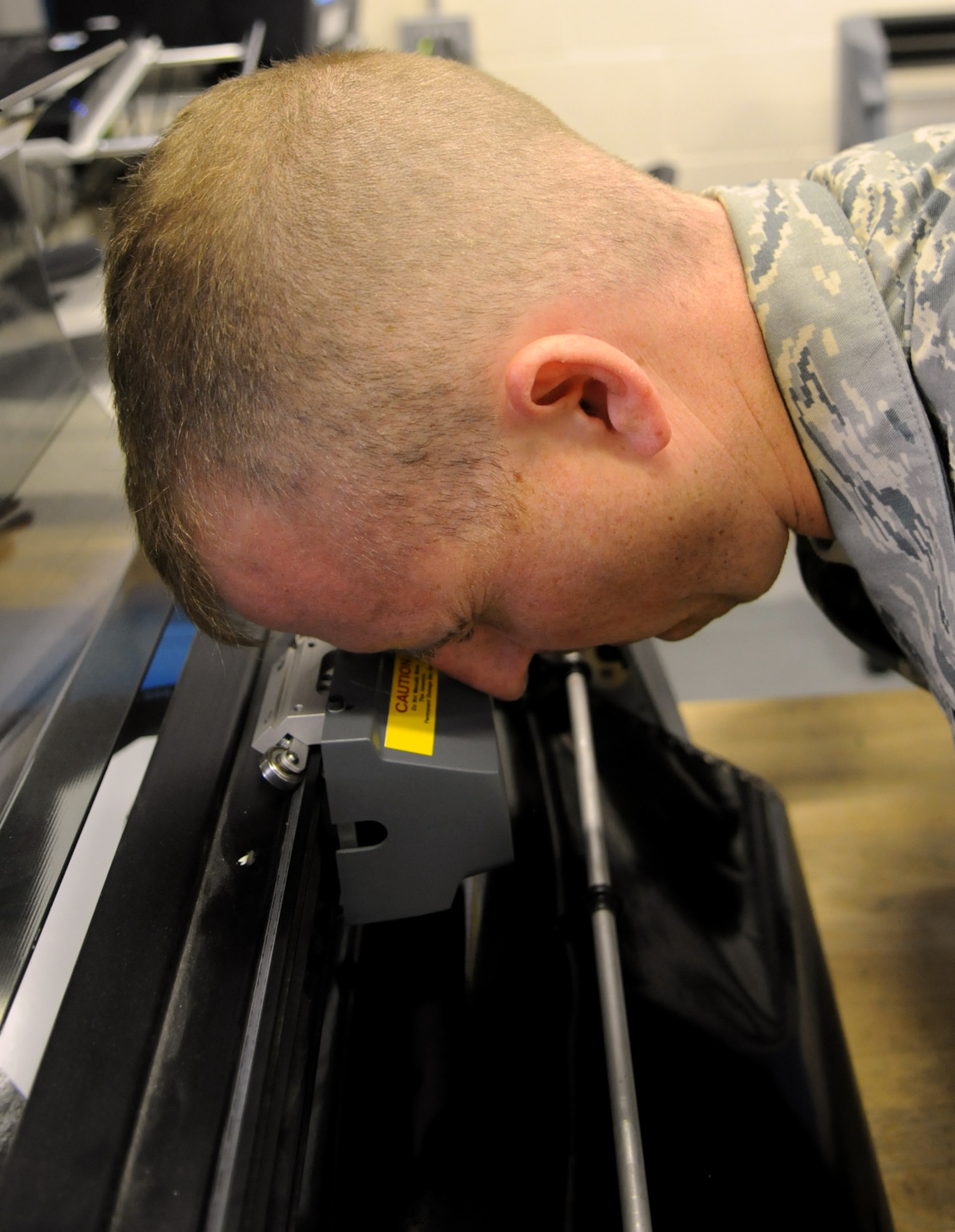 RAF MILDENHALL, England -- Aircraft Structural Maintenance craftsman Staff Sgt. Christopher Breaux uses a “bomb sight” to line up a precision cutting blade on an automated machine which will be used to score the material of a new decal.  The 100th Air Refueling Wing’s corrosion control shop creates decals and applies paint to every aircraft needing it at RAF Mildenhall.   (U.S. Air Force photo by Staff Sgt. Austin M. May)