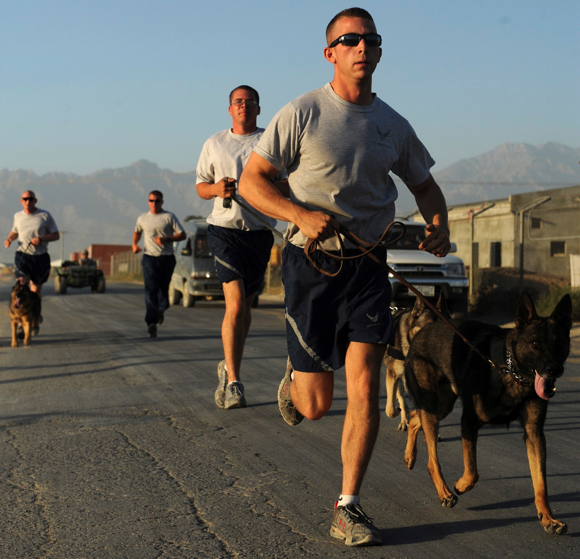 BAGRAM AIRFIELD, Afghanistan - (From left to right) Staff Sgt. Chris Reynolds, Tech. Sgt. Drew Odell, Staff Sgt. Justin Kitts and Staff Sgt. Scott Carpenter go on a training run Aug. 9. The dog handlers are deployed to the 455th Expeditionary Security Forces Squadron. K-9 units patrol the base and inspect mail, luggage, and vehicles. (U.S. Air Force photo/Staff Sgt. J.G. Buzanowski)