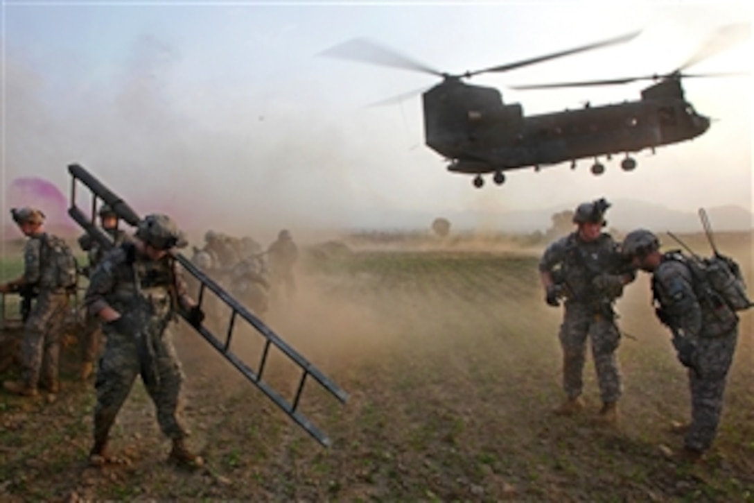 U.S. Army soldiers brace themselves as a CH-47 Chinook helicopter blows dust and rocks before landing during Operation Champion Sword in Khost province, Salerno, Afghanistan, Aug. 5, 2009. The soldiers are assigned to the 25th Infantry Division's 4th Brigade Combat Team, Focus Targeting Force.