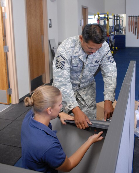 Master Sgt. Ronnel Ramos and Tech. Sgt. Martha Johnson assemble a reception desk at the fitness center, which is scheduled to open in Oct., 2009.  (U.S. Air Force photo/Staff Sgt. Alice Moore)