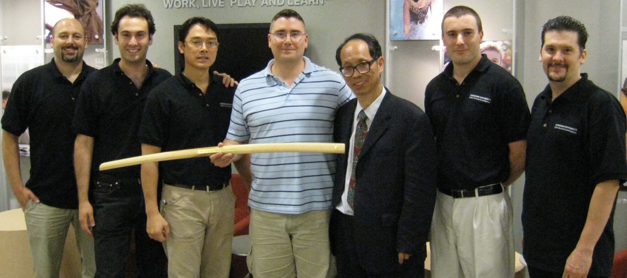 Capt. Michael Henson (center) displays a bokken he received after a cyberspace-based "capture the flag" event held by the New York City chapter of Infragard July 21-22. Captain Henson, an assistant professor of computer science at the U.S. Air Force Academy in Colorado Springs, Colo., started the Cadet Cyber Warfare Club to train cadets on network attack and defense skills. He was a member of an aggressor team during the event and appears here with members of the opposing Blue Team. (U.S. Air Force photo)