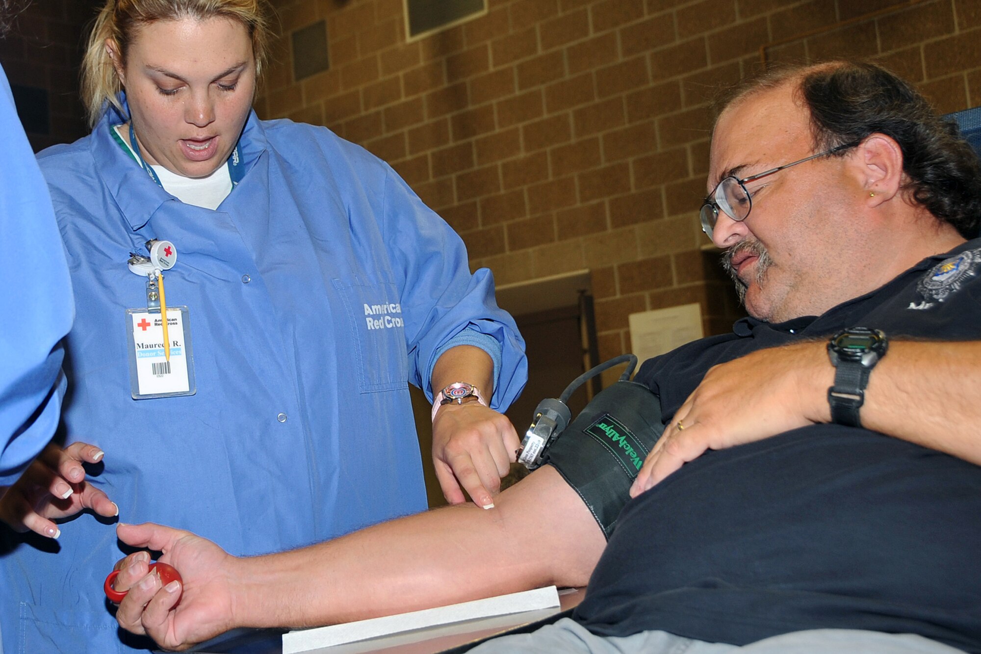 OFFUTT AIR FORCE BASE, Neb. - Kelly McConnell, chief of reports and analysis for the 55th Security Forces Squadron, squeezes a ball while Maureen Boot, an American Red Cross collection specialist, looks for a vein during a blood drive at the SFS Guardmount room, August 12. U.S. Air Force Photo by Jeff W. Gates.