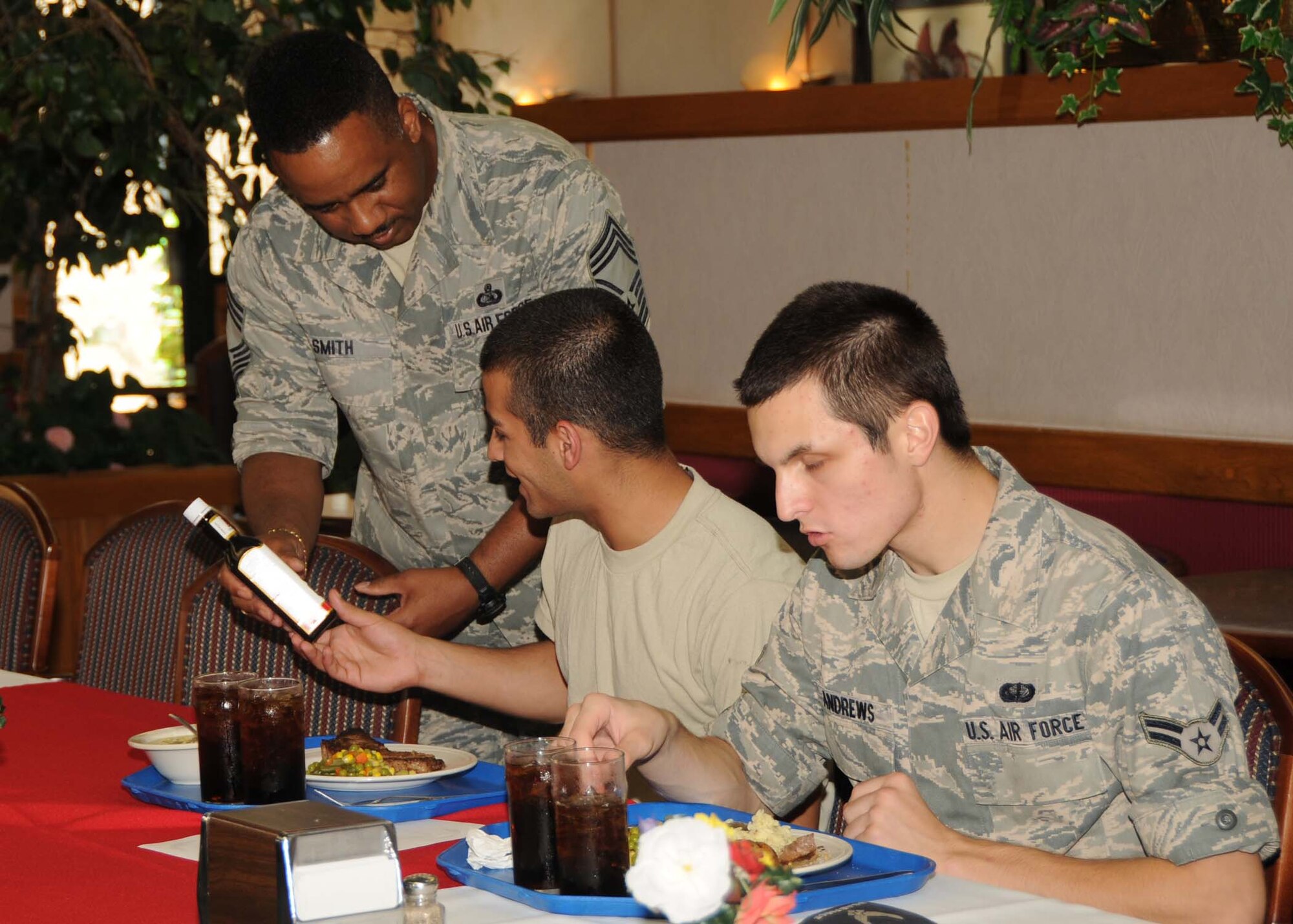 ALTUS AIR FORCE BASE, Okla. -- Airman 1st Class David Andrews (right),97th Force Support Squadron, joins Airman Rebwar Ebrahimi,97th Logistics Readiness Squadron,  as Chief Master Sgt. Raymond Smith (left), 97th Force Support Squadron, hands the steak sauce to him at the Quarterly Birthday Meal at the Solar Inn Dining Facility Aug. 13. The birthday meal is one of the man quality of life initiatives implemented by base leadership to boost Altus Airmen’s morale. (U.S. Air Force Photo/Senior Airman Marianne E. Lane)