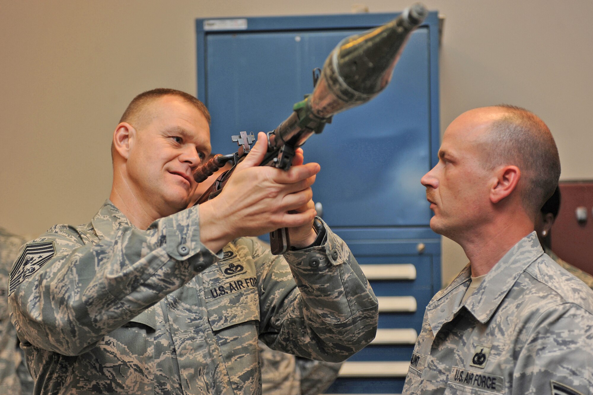 Chief Master Sgt. of the Air Force James Roy examines a demonstration weapon as Tech. Sgt. Charles Glunt shows how to use it during a July 29 tour at the U.S. Air Force Expeditionary Center on the Fort Dix section of Joint Base McGuire-Dix-Lakehurst, N.J. Chief Roy visited the U.S. Air Force Expeditionary Center on Fort Dix and McGuire Air Force Base to learn more about expeditionary training and operations in both areas. Sergeant Glunt is assigned to the U.S. Air Force Expeditionary Center armory. (U.S. Air Force Photo/Staff Sgt. Nathan G. Bevier)