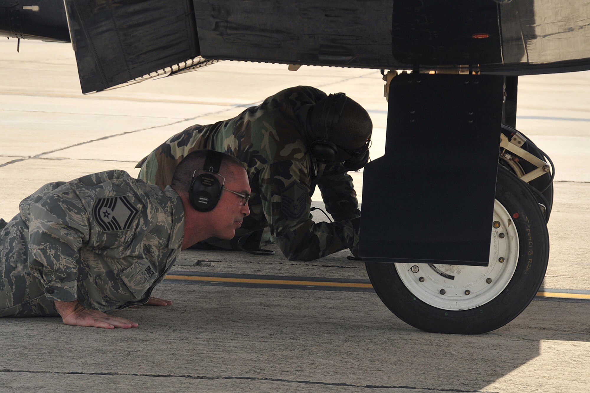 Senior Master Sgt. Rob Grover (left) and Master Sgt. Brian Carroll (right) check tire wear and temperature immediately after nine high speed taxis and 14 landings with the engine running. Wear and handling characteristics were documented in support of the T-6 Radial Tire Test. (U.S. Air Force photo by Terry Moore)