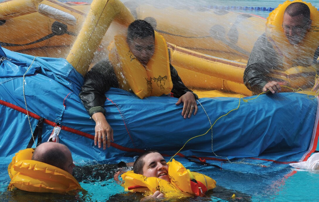 Members of the 1st Airlift Squadron and 99th Airlift Squadron take part in a water survival exercise to refresh their Survival, Evasion, Rescue and Escape, or SERE, training they learned at Fairchild AFB, Wash., at the base pool recently. Andrews SERE instructors strive to create real-life SERE situations by utilizing high pressure fire hoses to simulate powerful rain. (U.S. Air Force photo/ Airman 1st Class Melissa Rodrigues)
