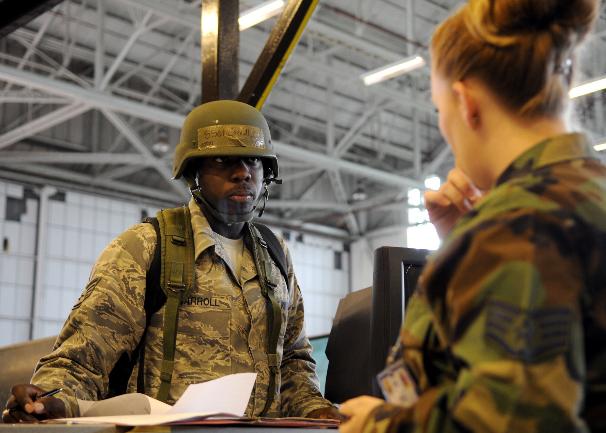 RAF MILDENHALL, England - Staff Sgt. Courtney Carroll, 100th Air Refueling Wing, Paralegal, runs through the processing line while Staff Sgt. Melissa Striggles, 100th Force Support Squadron, assists him during the Phase I portion of an exercise Aug. 13. (U.S. Air Force Photo by Staff Sgt. Jerry Fleshman)