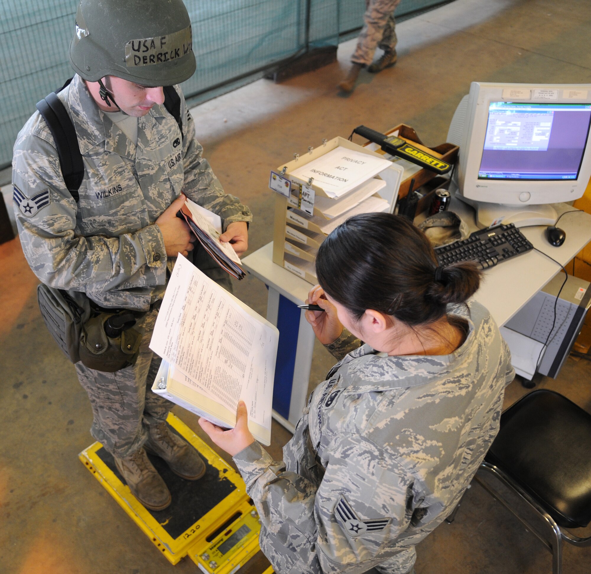RAF MILDENHALL, England - Senior Airman Derrick Wilkins, metals technology journeyman, 100th Maintenance Squadron, step ups on the scale while Senior Airman Maria Bair, 100th Logistics Readiness Squadron, takes his weight while inprocessing during the Phase I portion of an exercise Aug. 13. Airmen participate in the exercises to practice for possible real world deployments. (U.S. Air Force photo by Staff Sgt. Jerry Fleshman)