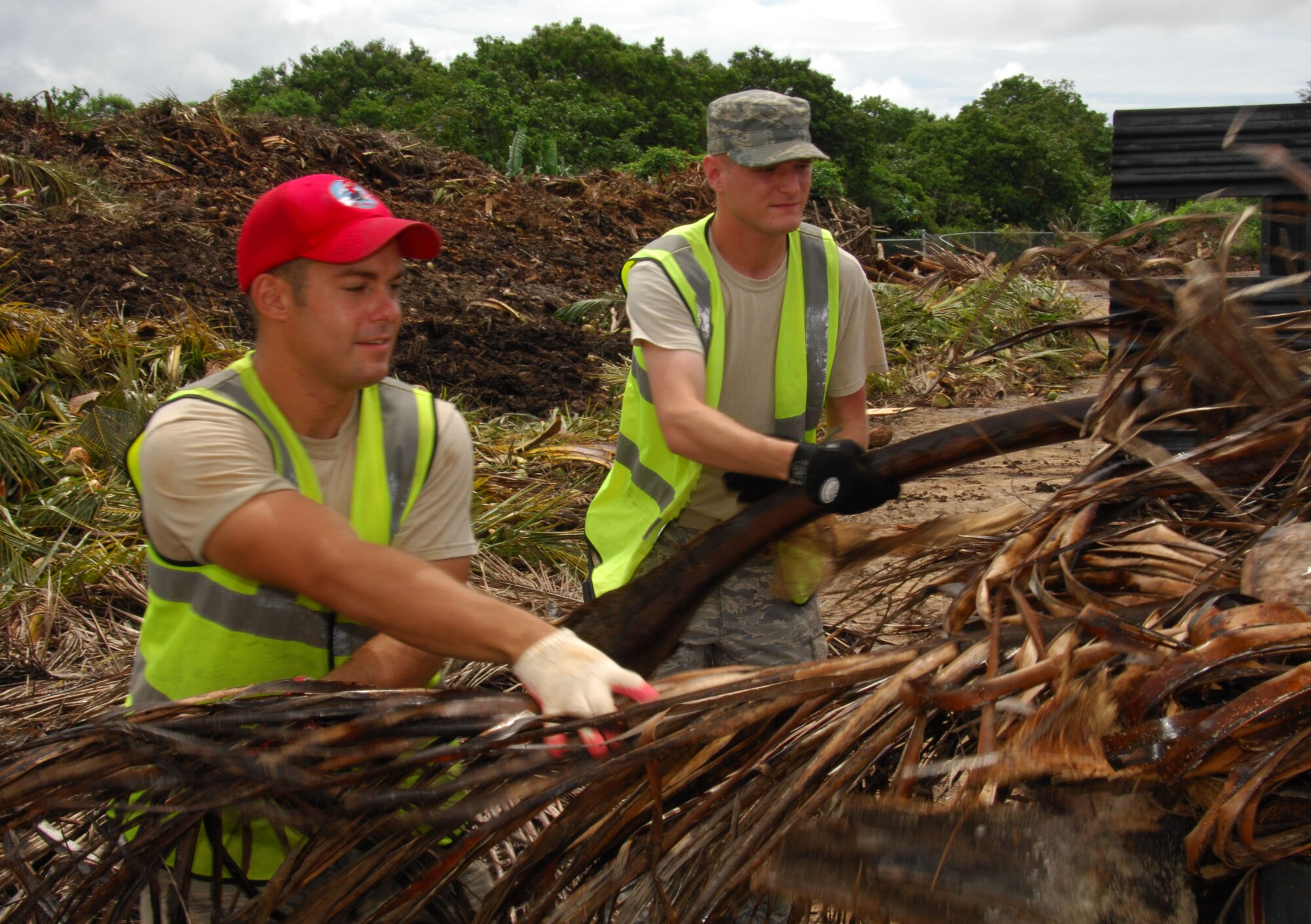 ANDERSEN AIR FORCE BASE, Guam ? Senior Airman Paul Triggs, 554th RED HORSE Squadron vehicle maintenance, and Senior Airman Matthew Hubbard, 734th AMS information controller, unload palm fronds and debris from a truck at the base landfill here August 4. The Airmen were volunteers in support of Andersen's base pride detail program. (U.S. Air Force photo by Senior Airman Shane Dunaway)