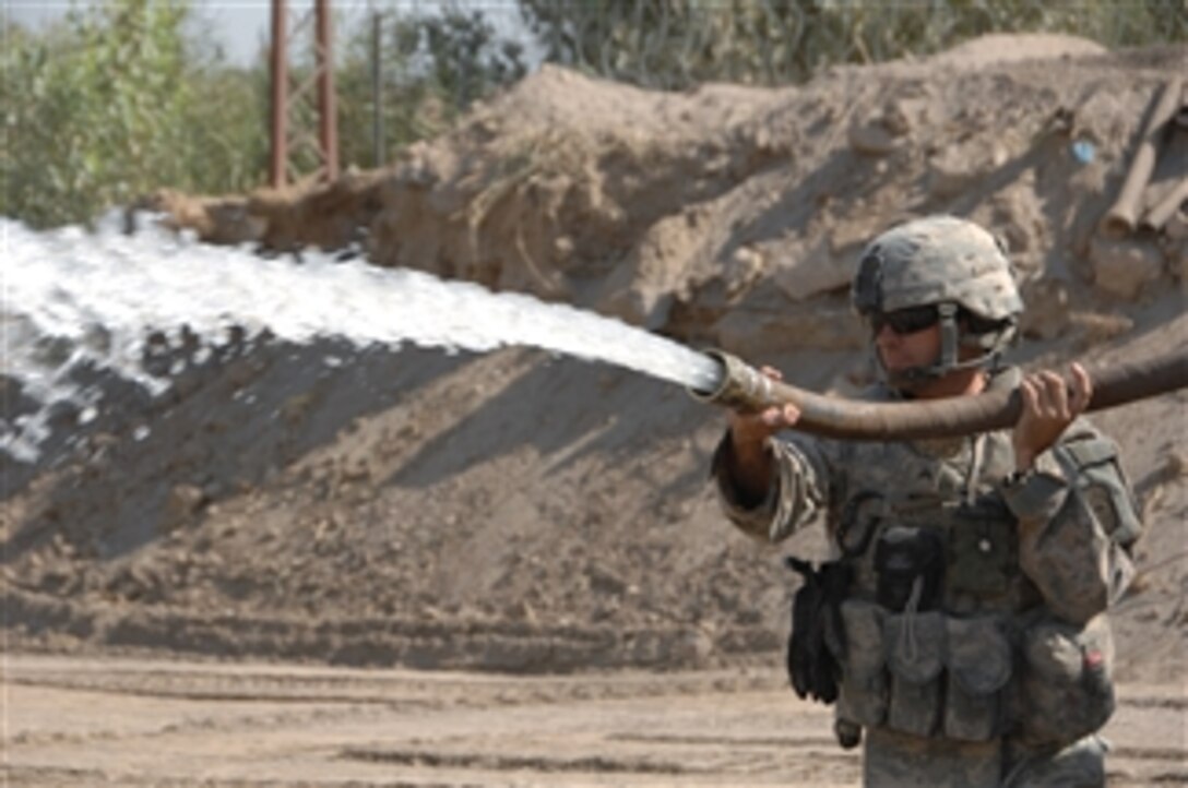 U.S. Army Sgt. Thomas Pearson, assigned to 277th Engineers Company, 416th Engineering Brigade, waters the ground to help compact the sand near the Tigris River in Baghdad, Iraq, on Aug. 10, 2009.  