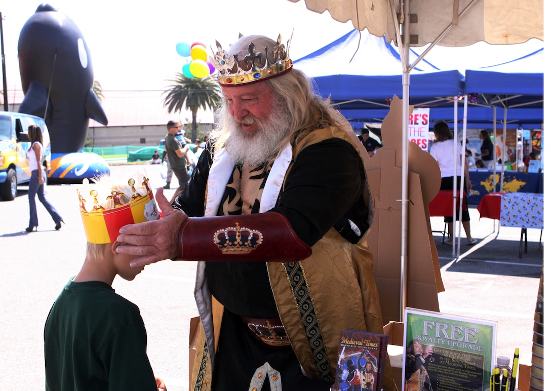 Fredy Ingles, who plays King Filipe at Medieval Times, gives a paper crown to Seth Conner. The eight year old explored the ITT Latitudes & Travel Expo with his mother Petty Officer 1st Class Farrah Ocasio, corpsman, Marine Aircraft Group 39, Marine Corps Air Station Camp Pendleton.