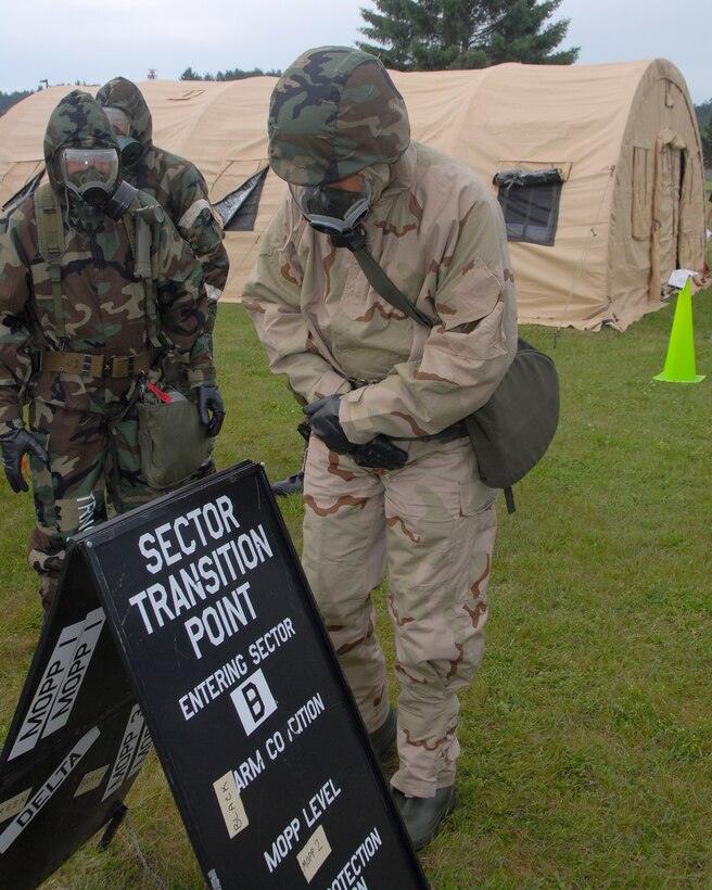 Members of the 123rd Airlift Wing practice chemical decontamination procedures as they travel from one sector to another following a simulated attack at Volk Field, Wis.