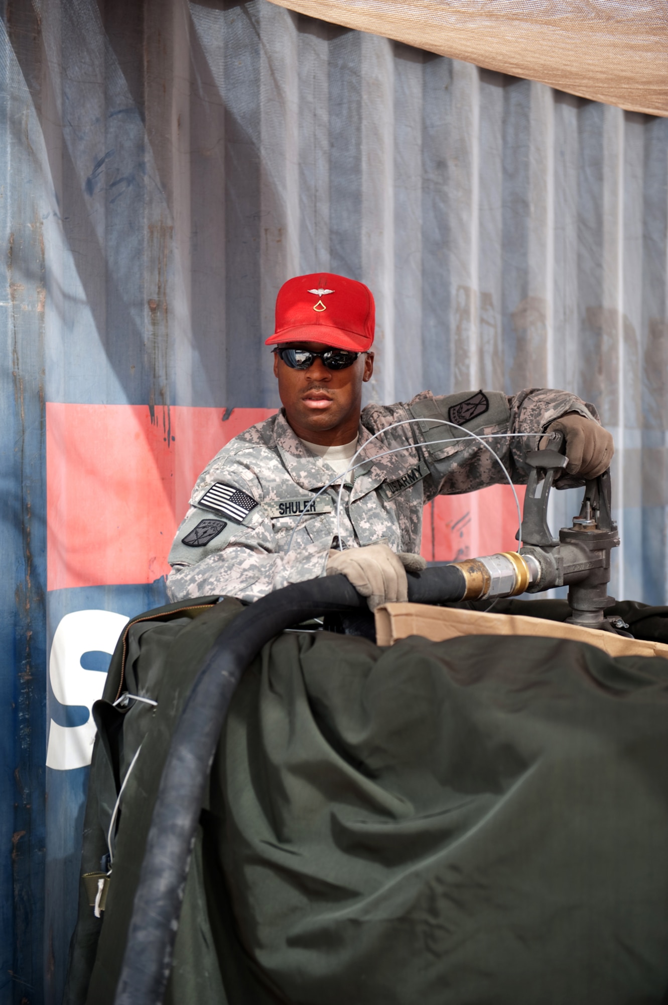 U.S. Army Pfc. Kiel Shuler, Detachment 8, 24th Quartermaster Company, 593rd Special Troop Battalion parachute rigger, fills barrels with JP-8 fuel, Aug 6, which will be air dropped to various locations throughout Southwest Asia.  Private Shuler is deployed from Fort Bragg, N.C. in support of Operations Iraqi and Enduring Freedom. (U.S. Air Force Photo/Staff Sgt. Robert Barney)