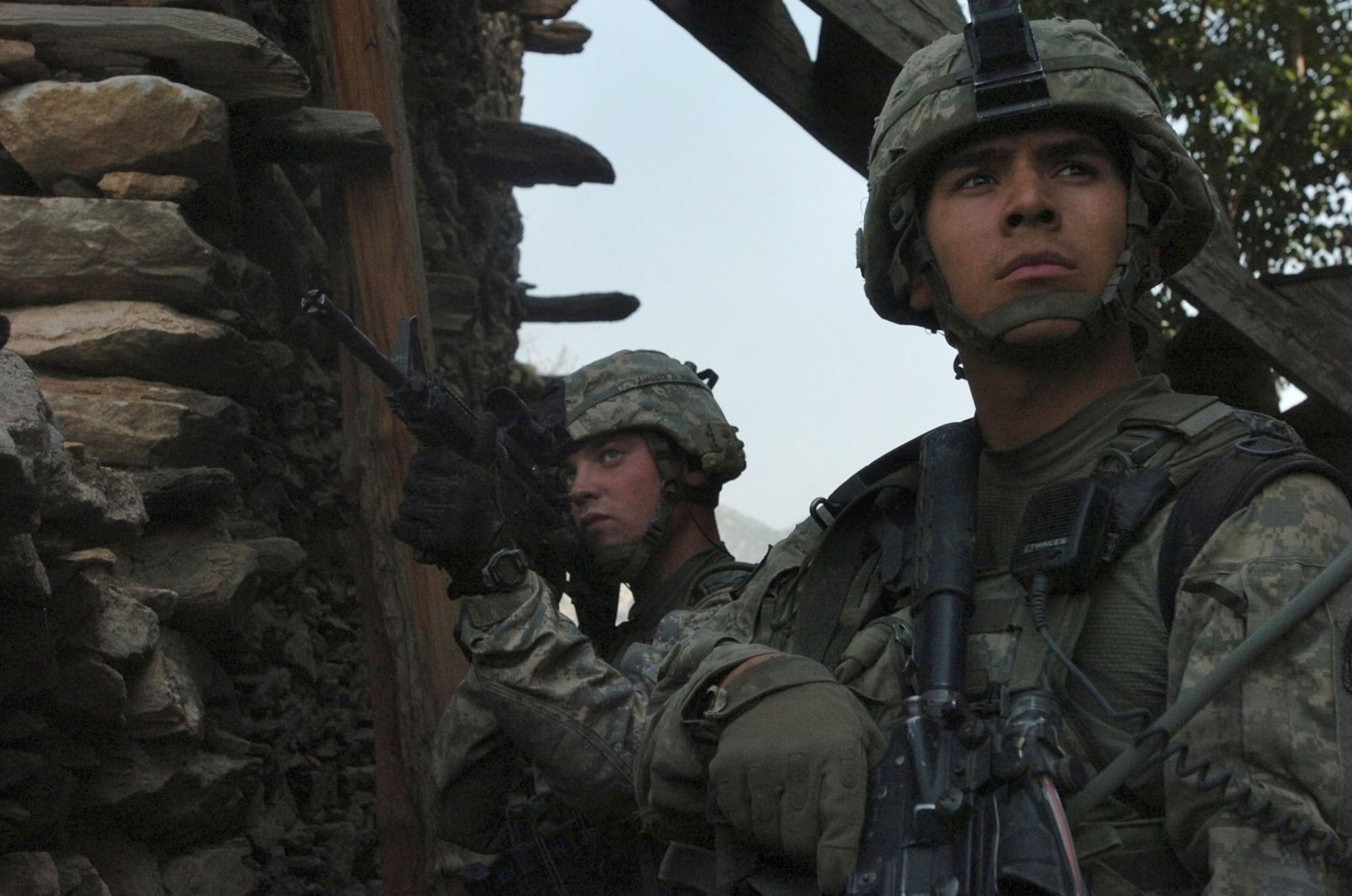KUNAR PROVINCE, Afghanistan - A U.S. Army Soldier and U.S. Air Force Airman scan the Korengal valley's rocky hillside as fellow members return fire at insurgents, during an early morning gun battle in the Korengal valley of Kunar province, Afghanistan, Aug. 13. Both service members are attached to Company B, 2nd Battalion, 12th Infantry Regiment, 4th Brigade Combat Team, 4th Infantry Division, based at Fort Carson, Colo. International Security Assistance Forces across Afghanistan have increased operations in recent months, in order to ensure safety and security during Afghanistan's second national election, scheduled for the end of August. (U.S. Army photo/Sgt. Matthew Moeller)