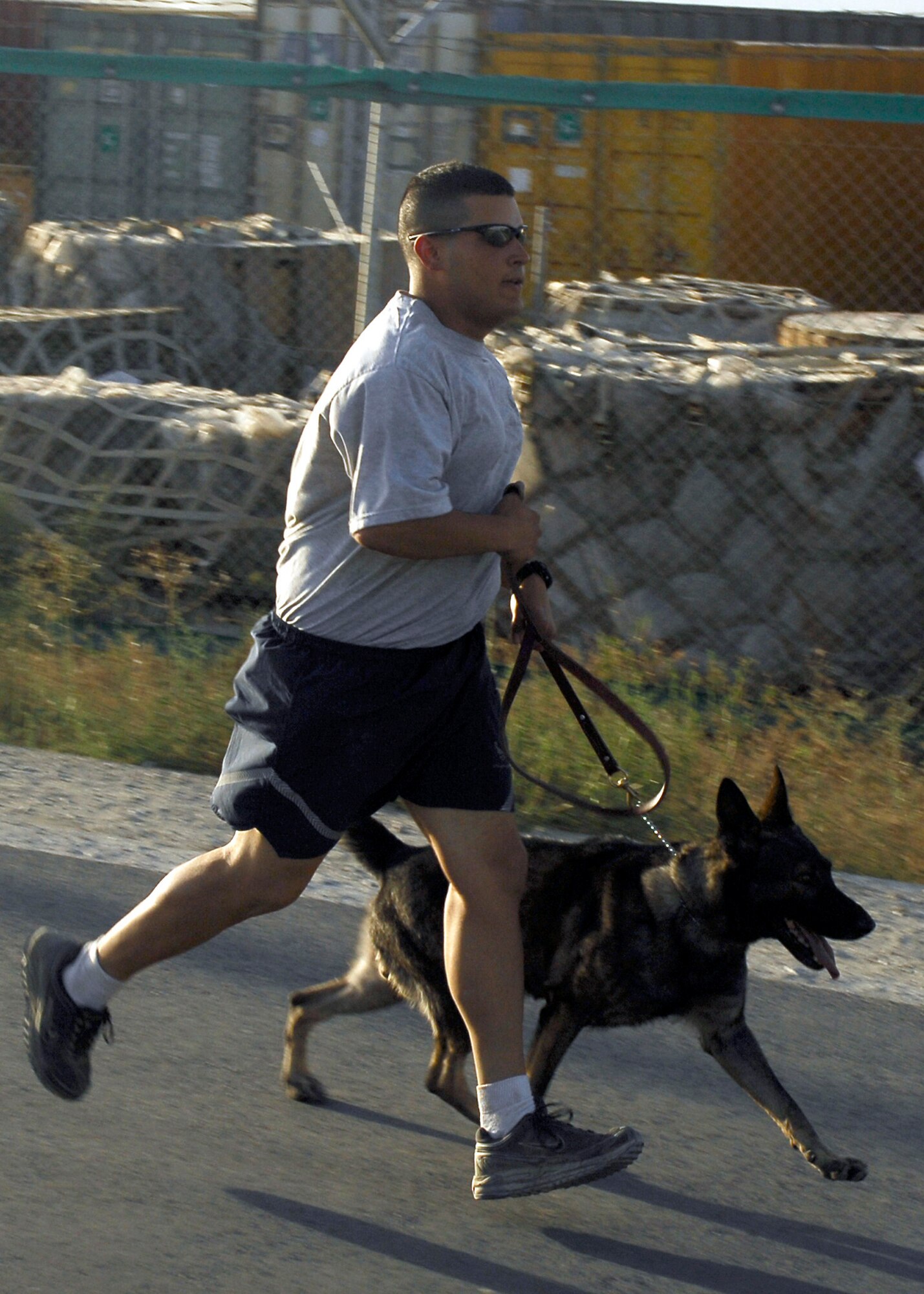 BAGRAM AIRFIELD, Afghanistan - Senior Airman John Spearing, from the 455th Expeditionary Security Forces Squadron, runs with his military working dog, Soyer, during a morale building run in order to stay fit and motivated, here Aug. 9. As the first dog teams on the ground for the 455th Air Expeditionary Wing, they walk the perimeter daily.  Airman Spearing hails from Pueblo, Colo., and he and Soyer are deployed from Robins  Air Force Base, Ga. (U.S. Air Force photo/Senior Airman Felicia Juenke)