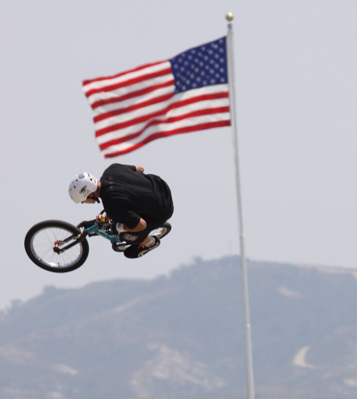 Vista-native Caleb M. Norman, a bicycle motocross rider with SRH Productions, spins his handle bars 30 feet in the air as he leaves the three-quarter pipe ramp on the 52-Area parade deck during the Marine Corps Community Services’ sponsored Semper X event, Aug. 15.