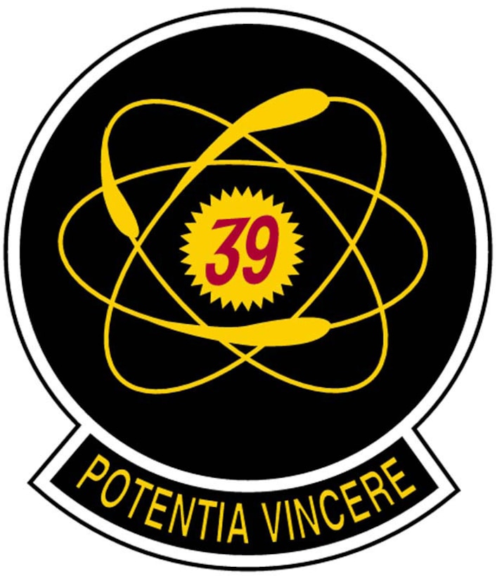 The patch consists of a red "39" within the nucleus of a yellow atom. The atom is set on a dark blue circle, ringed by a silver border. At the bottom is the squadron motto, "Potentia Vincere", which is Latin for "The power to conquer". The atom represents the unlimited abilities in each squadron member, and the unity of the squadron as a whole. The colors represent the four classes, and the unified design represents the cooperation necessary among the classes to insure an effective squadron. This was the squadron's original patch, which was discontinued in 1980, but revived in 1991. 