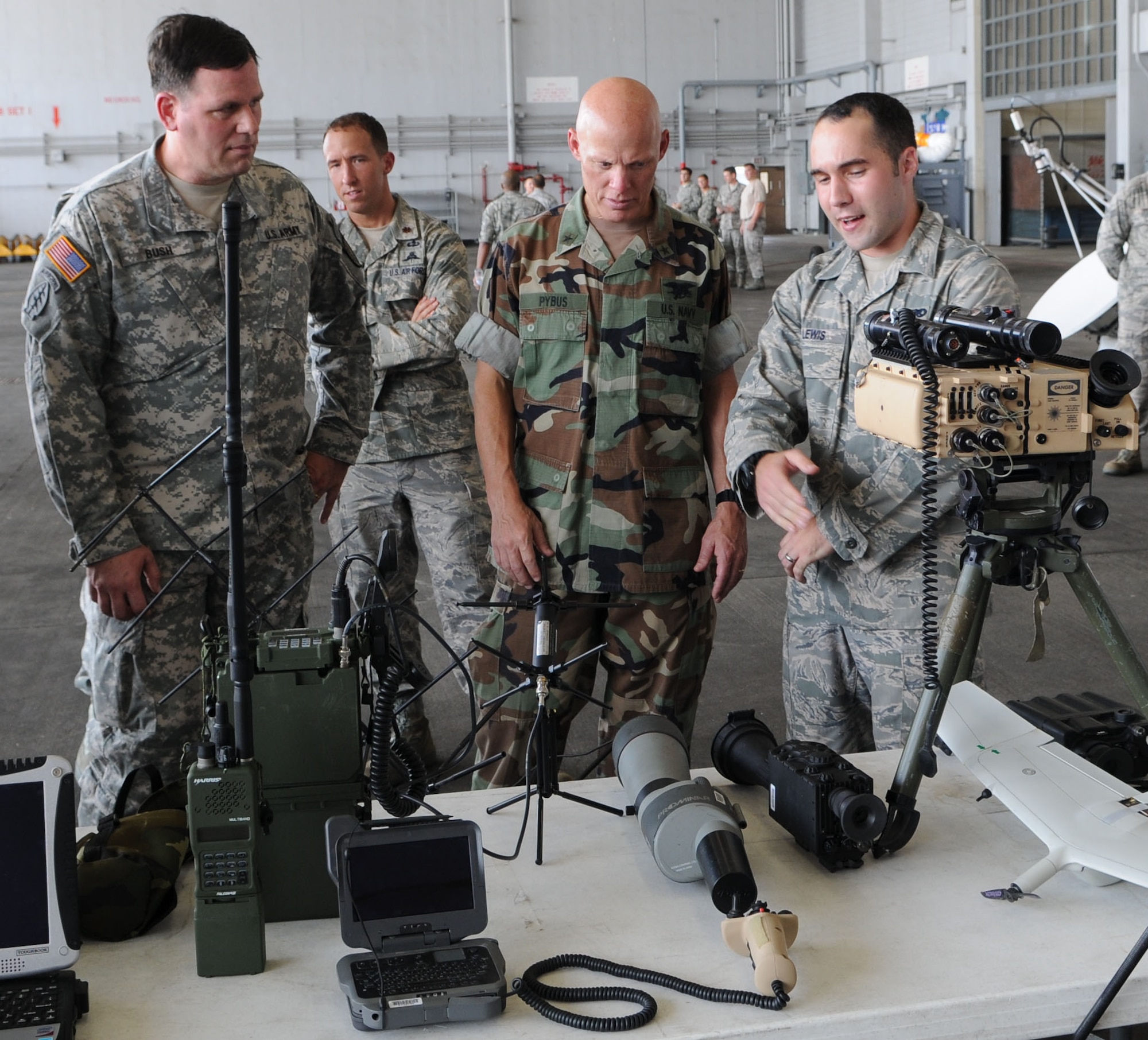 KADENA AIR BASE, Japan -- Senior Airman Norman Lewis (right), 320th Special Tactics Squadron, briefs Rear Adm. Sean Pybus (center), the commander of Special Operations Command, Pacific, and Command Sgt. Maj. Stephen Bush, the senior enlisted advisor for Special Operations Command, Pacific, on equipment used by members of the 320th STS to support air, ground, and maritime combat operations. This was Rear Adm. Pybus' first visit to the 353rd SOG since taking command of SOCPAC June 12. The 353rd SOG is SOCPAC's air component command responsible for command and control of all SOF air in the Pacific AOR.  This visit focused on orienting Rear Adm. Pybus and Command Sgt. Maj. Bush on the group's mission and capabilities. (U.S. Air Force Photo by Tech. Sgt. Aaron Cram) 